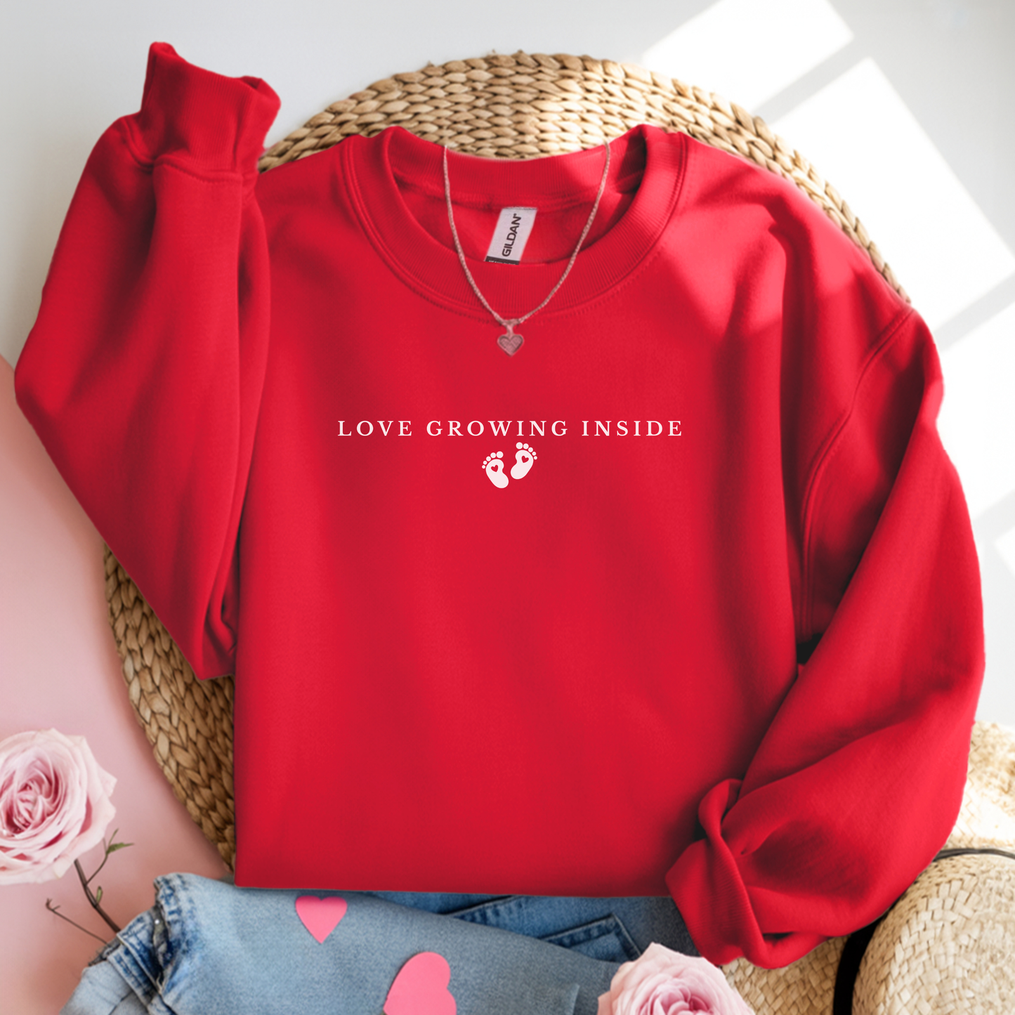 Red sweatshirt with 'Love Growing Inside' text on a woven surface