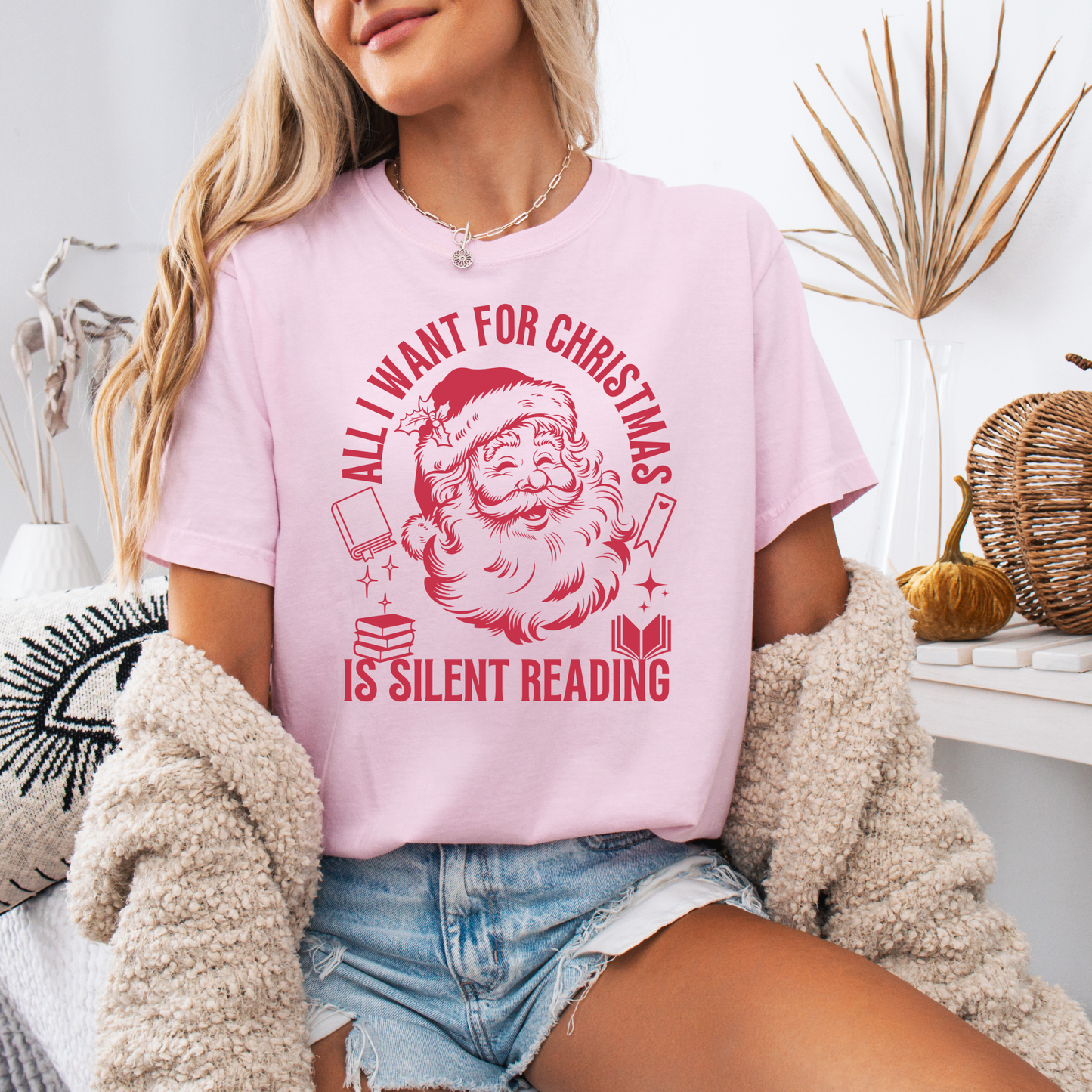 Woman wearing a light pink Christmas graphic tee with vintage Santa and the phrase “All I Want for Christmas Is Silent Reading.”