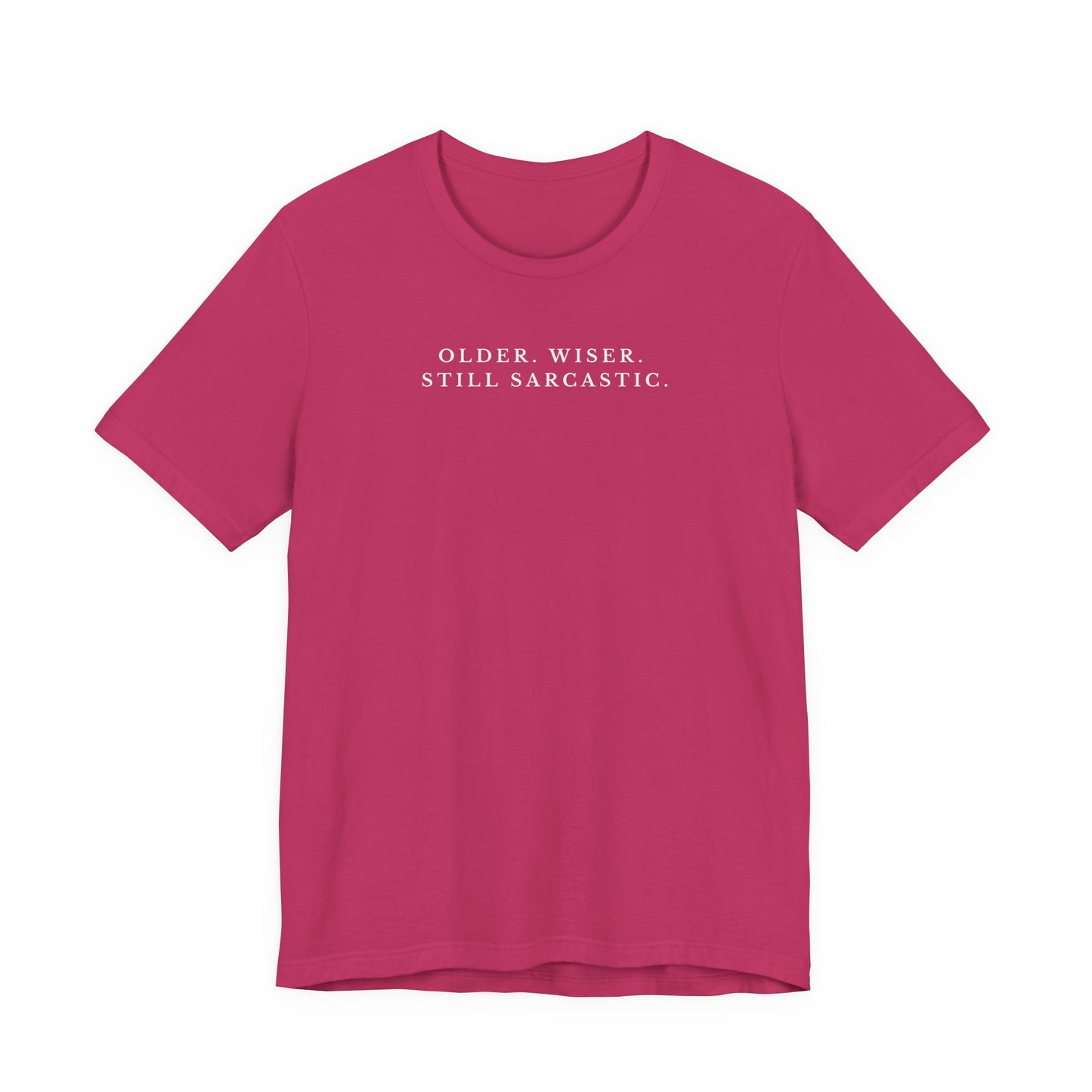 Pink t-shirt with white text saying "older. wiser. still sarcastic." on a white background
