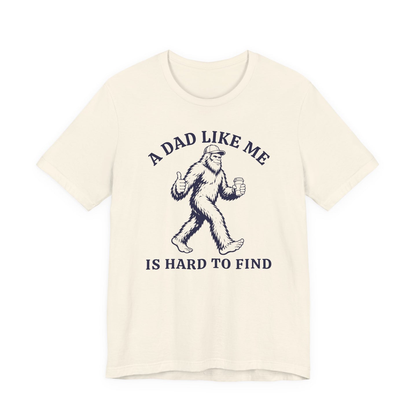 Bella + Canvas 3001 t-shirt in natural featuring a funny Bigfoot dad design with a Sasquatch holding a coffee cup and thumbs up alongside the phrase “A Dad Like Me Is Hard To Find” in navy blue lettering.