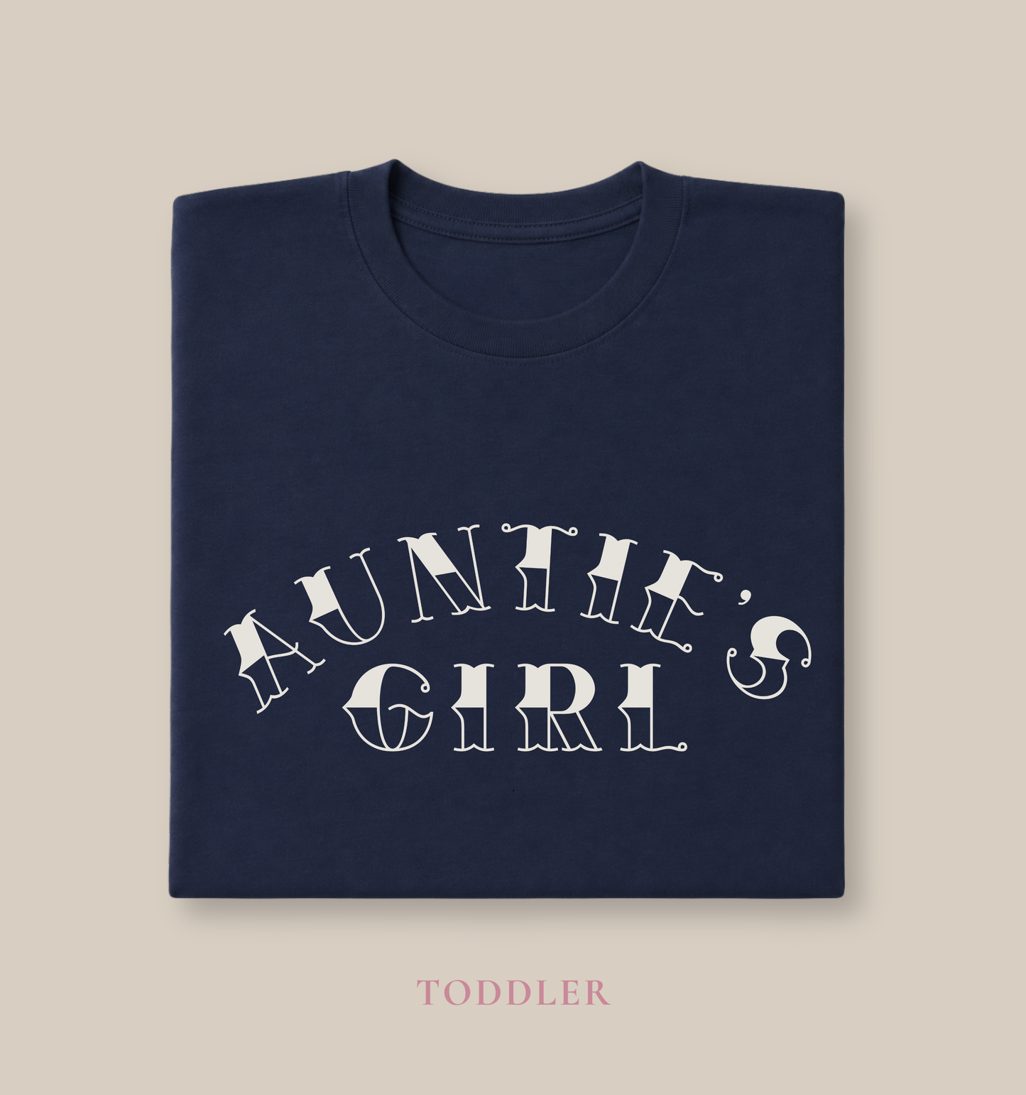 Folded navy Bella + Canvas 3001T toddler t-shirt featuring white “Auntie’s Girl” graphic lettering in a trendy vintage-inspired font on a minimalist boutique style design.
