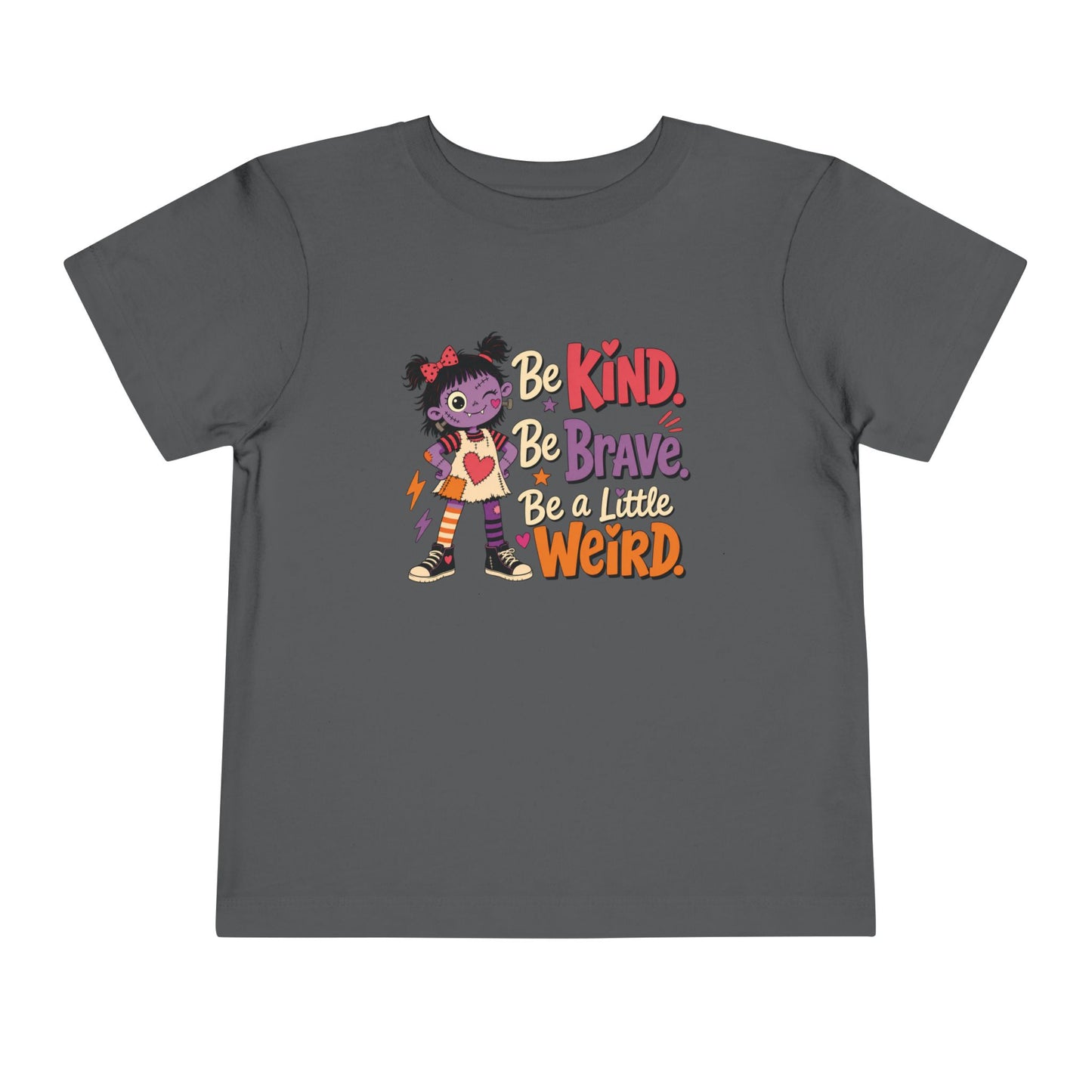 Asphalt grey toddler T-shirt featuring a colorful stitched doll, hearts, stars, and the phrase “Be Kind, Be Brave, Be a Little Weird.”