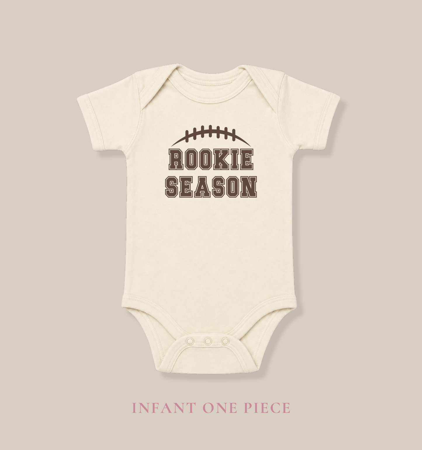 Baby wearing a Bella + Canvas 100B natural infant bodysuit featuring a brown football graphic and "Rookie Season" text, perfect for football season, game days, baby showers, and newborn sports fans.