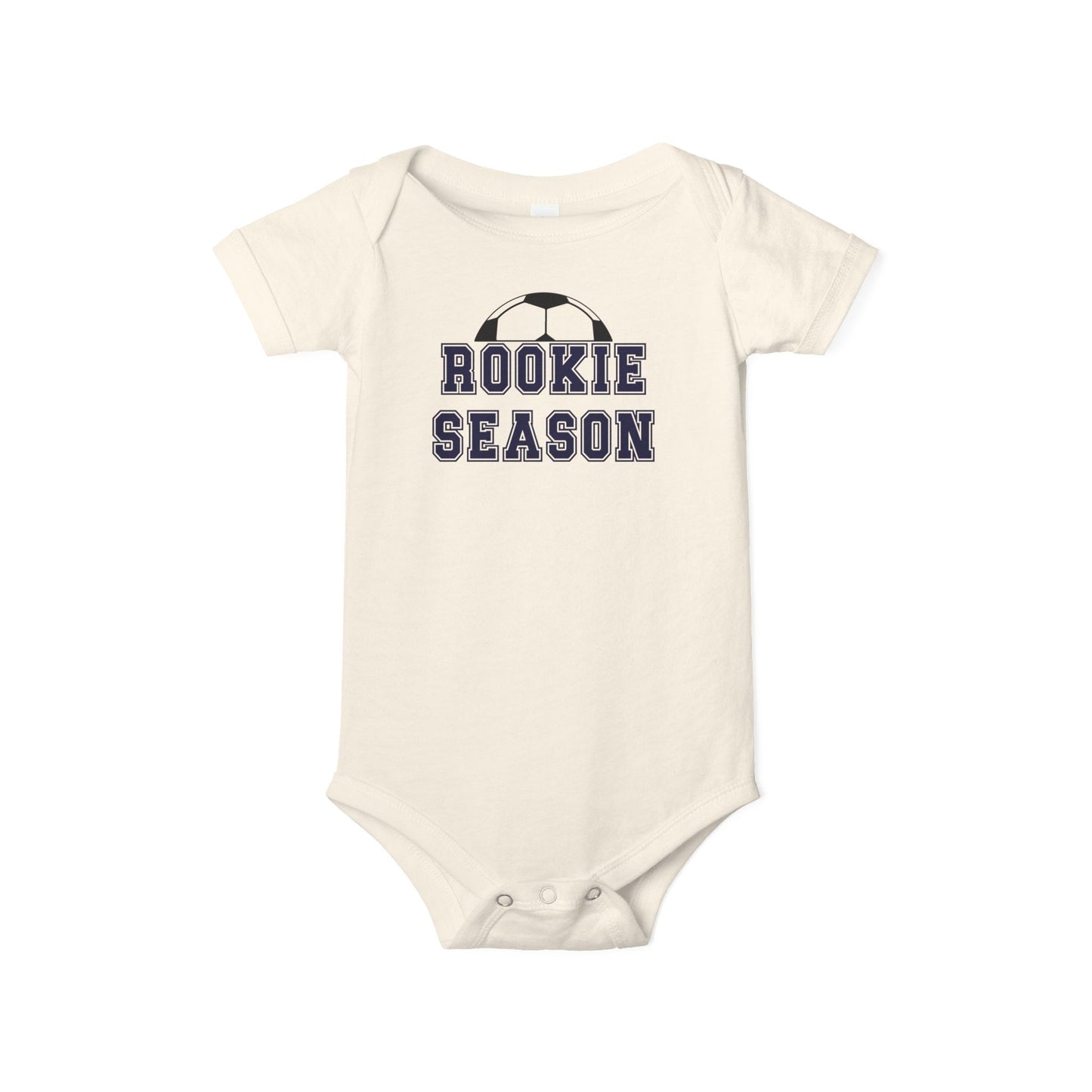 Bella + Canvas 100B baby bodysuit in natural featuring the phrase “Rookie Season” in navy varsity lettering with a soccer ball graphic. Soccer-themed infant one-piece for baby boys and girls, perfect for first soccer season, game day outfits, soccer family photos, baby shower gifts, and little future soccer stars.