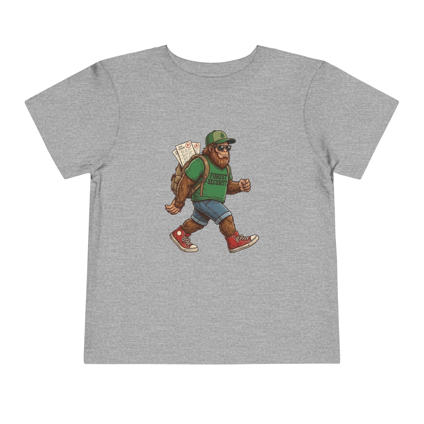Bella + Canvas 3001T toddler t-shirt in athletic heather gray featuring a walking Bigfoot student graphic wearing sunglasses, a green Forest Security shirt, backpack with school papers, denim shorts, and red sneakers. Fun back-to-school design for toddlers displayed on a neutral background.