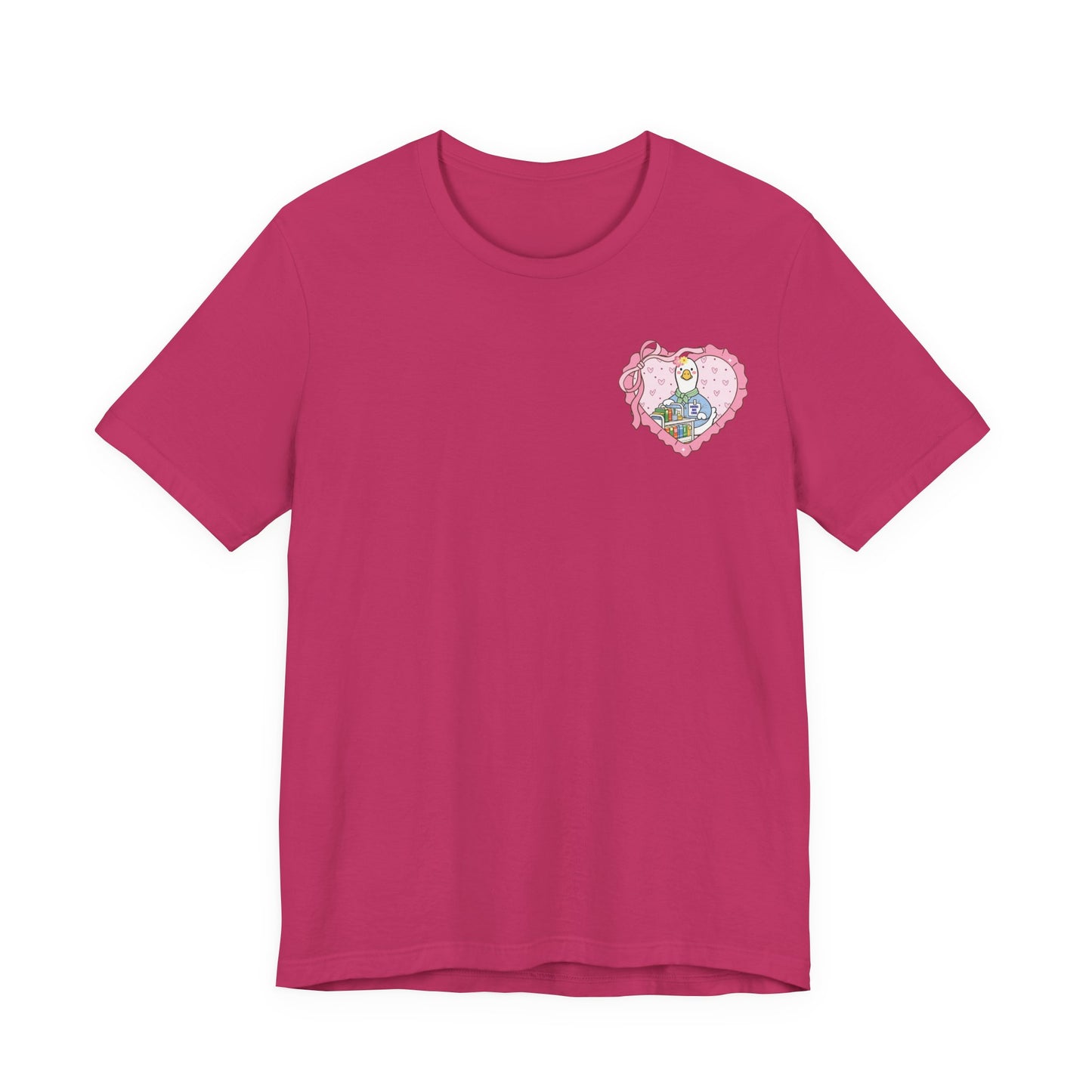 Bella + Canvas 3001 t-shirt in Berry featuring a coquette school librarian goose pocket design. The artwork shows a white goose behind a colorful library book cart inside a pink heart with ribbon details. Cute librarian shirt for school librarians, media specialists, and book lovers.