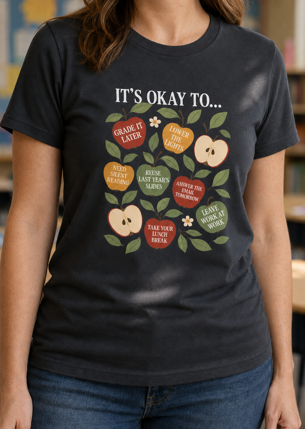 Bella + Canvas 3001 unisex t-shirt in Dark Grey featuring the phrase "It's Okay To..." with colorful apples displaying teacher self-care reminders like "Grade It Later," "Take Your Lunch Break," "Leave Work at Work," and "Answer That Email Tomorrow." A thoughtful teacher appreciation graphic tee promoting educator wellness and work-life balance.