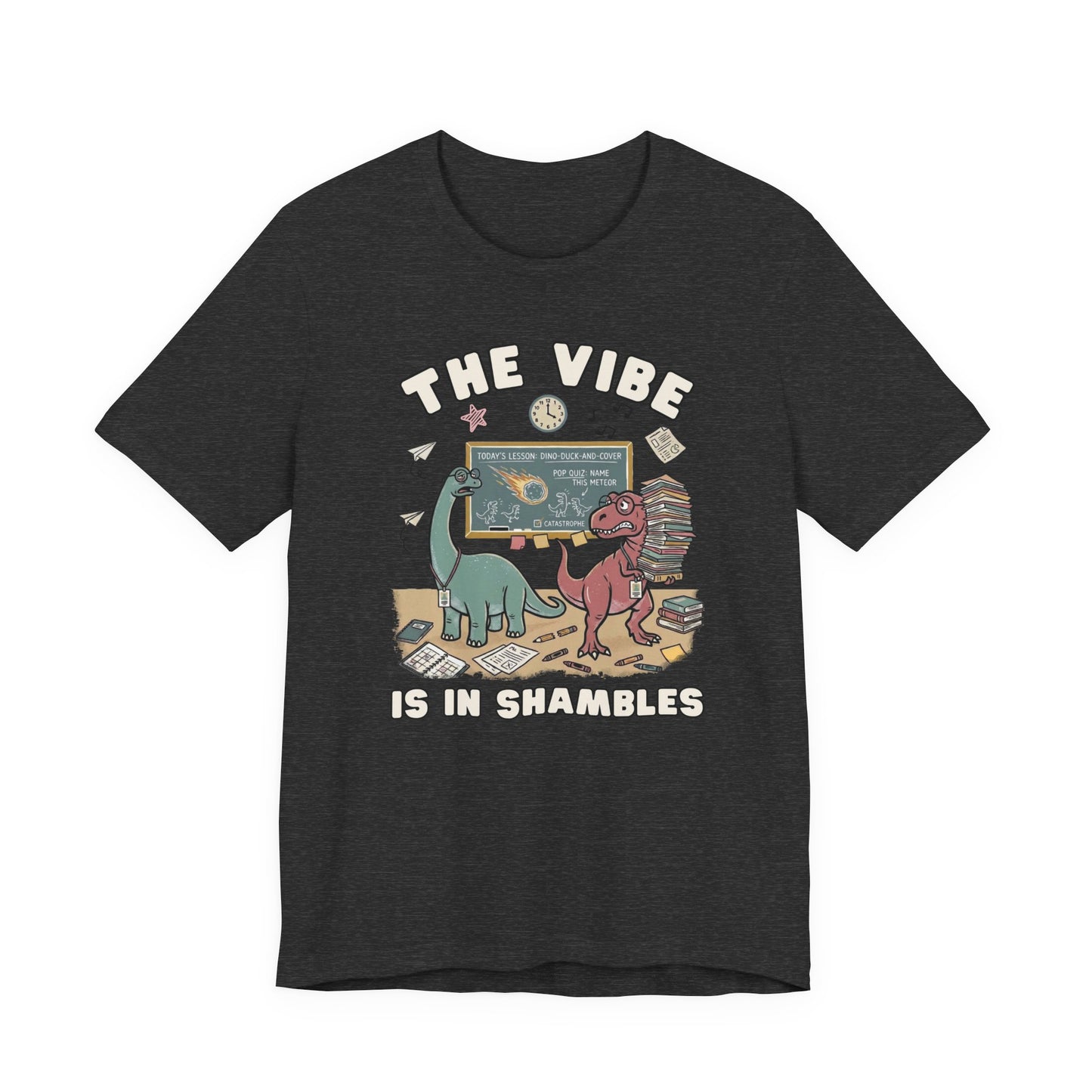 Bella + Canvas 3001 dark heather grey teacher t-shirt featuring two overwhelmed dinosaurs in a cluttered classroom with books, papers, and a chalkboard. Funny teacher graphic tee with "The Vibe Is In Shambles" design, ideal for teachers, educators, classroom humor, back-to-school outfits, and teacher gifts.