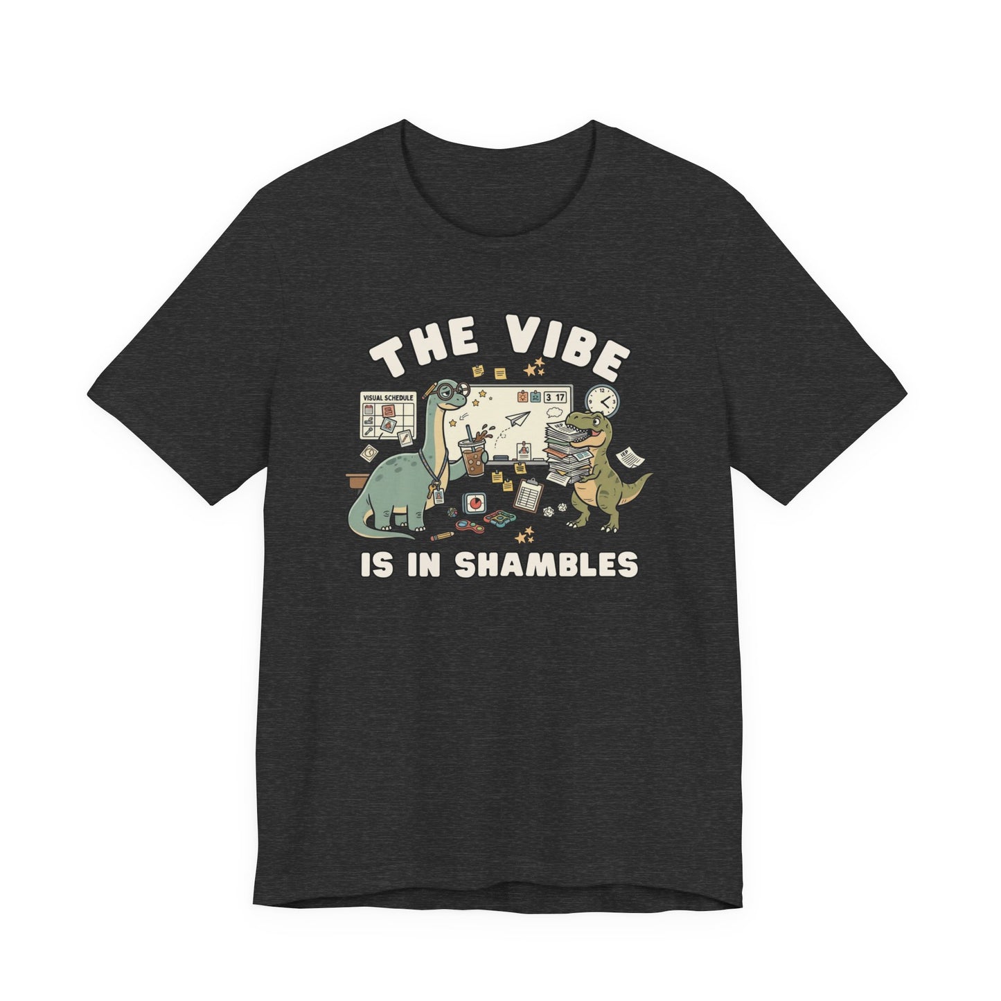 Bella + Canvas 3001 heather athletic dark grey t-shirt featuring a funny special education teacher dinosaur design with the phrase "The Vibe Is In Shambles." The graphic includes dinosaurs surrounded by visual schedules, classroom supplies, paperwork, fidget toys, a clock, and teaching materials. Perfect for special education teachers, IEP teachers, paraprofessionals, school counselors, and educators who bring humor to busy classroom days.