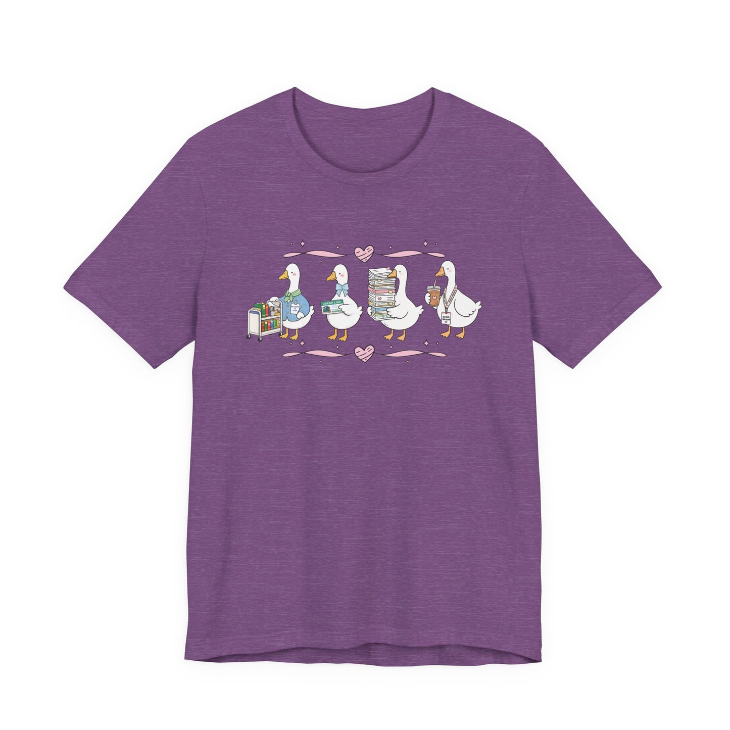 Bella + Canvas 3001 t-shirt in Heather Team Purple featuring a coquette librarian goose design. Four white geese display a library book cart, library card, stack of books, and iced coffee with a school librarian badge. Pink hearts and ribbon accents add a whimsical touch, making this cute librarian shirt perfect for school librarians, media specialists, library staff, book lovers, teacher appreciation gifts, and back-to-school outfits.