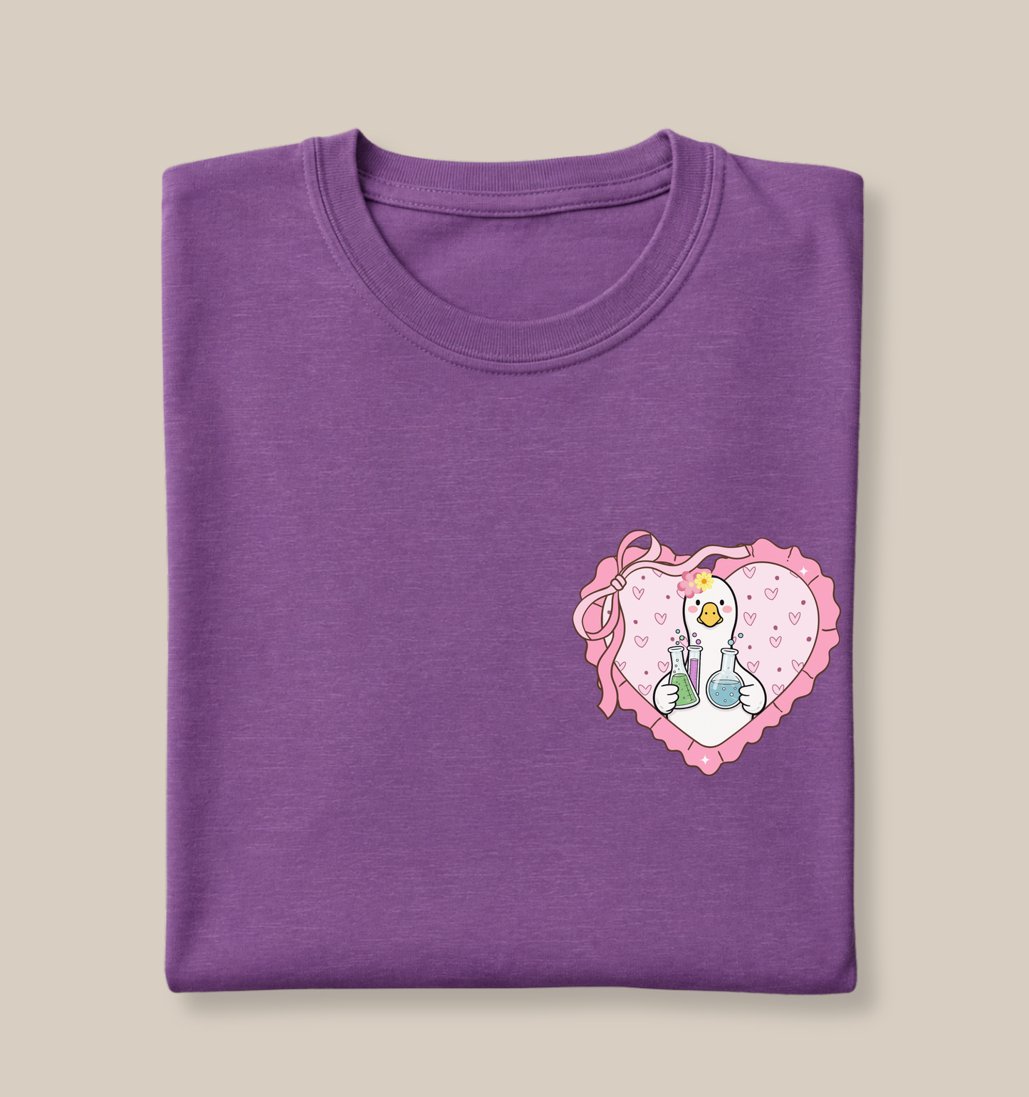 Bella + Canvas 3001 t-shirt in Heather Team Purple featuring a coquette science teacher goose heart design on the left chest. The design shows a white goose holding laboratory beakers inside a pink heart with ribbon bow details. Perfect for science teachers, chemistry teachers, biology teachers, STEM educators, teacher appreciation gifts, and back-to-school outfits.