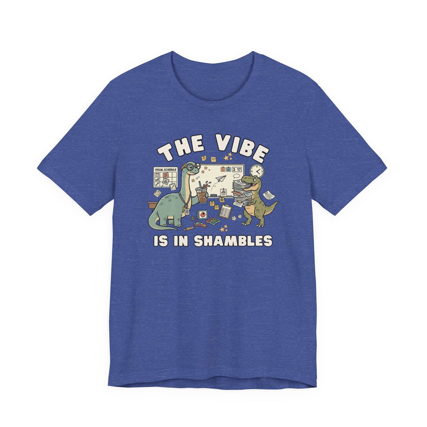 Bella + Canvas 3001 heather true royal blue t-shirt featuring a humorous special education teacher dinosaur design with the phrase "The Vibe Is In Shambles." The graphic includes dinosaurs surrounded by visual schedules, classroom supplies, paperwork, fidget toys, a clock, and educational tools. A fun teacher shirt for special education teachers, IEP case managers, paraprofessionals, school staff, and educators who understand the organized chaos of the classroom.