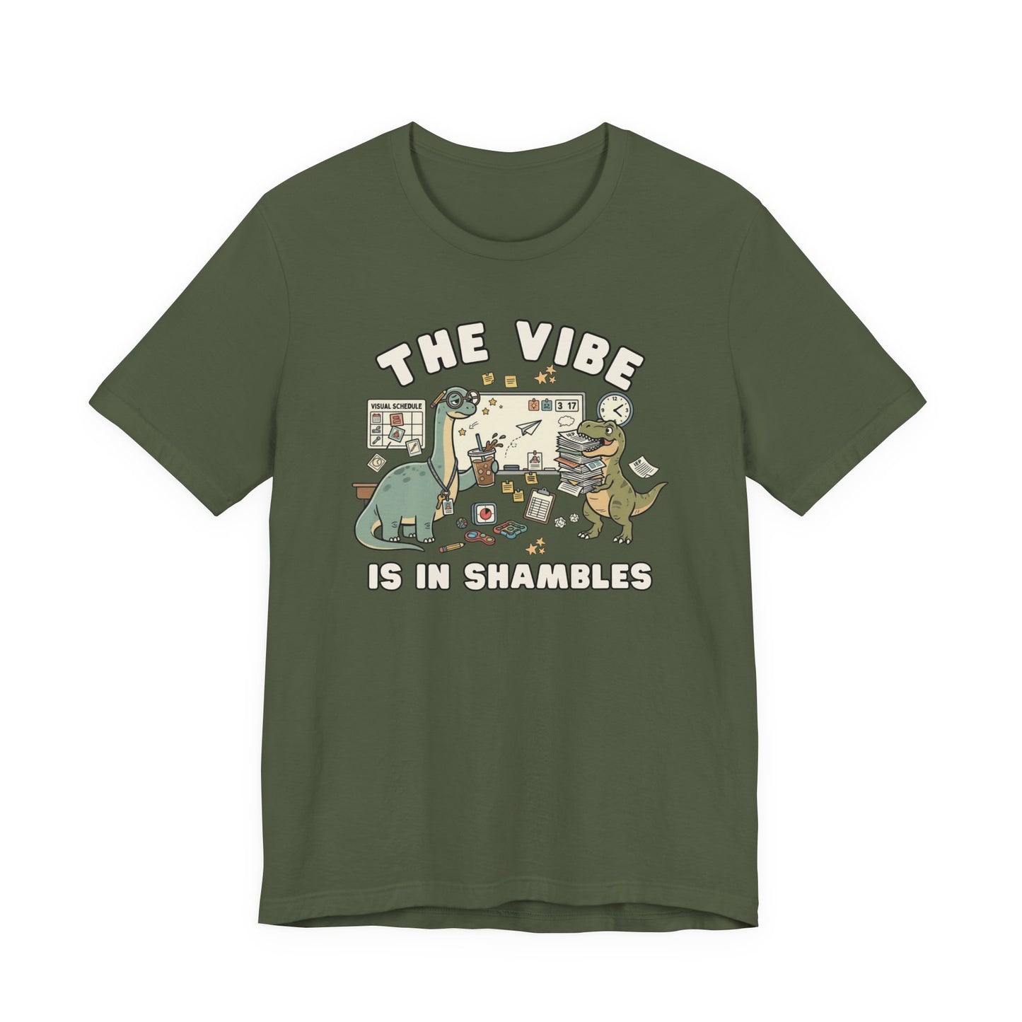 Bella + Canvas 3001 military green t-shirt featuring a humorous special education teacher dinosaur design with the phrase "The Vibe Is In Shambles." The graphic includes dinosaurs surrounded by visual schedules, classroom supplies, paperwork, fidget toys, a clock, and educational tools. Perfect for special education teachers, IEP case managers, paraprofessionals, school staff, and educators who embrace classroom chaos with humor and style.