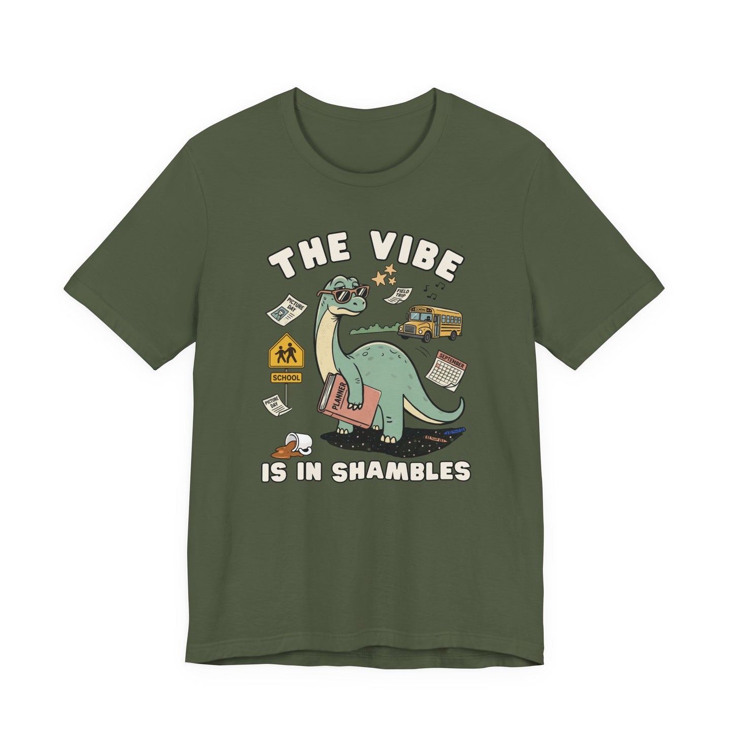Bella + Canvas 3001 military green t-shirt featuring a funny teacher dinosaur design with the phrase "The Vibe Is In Shambles." The graphic includes a dinosaur holding a planner and surrounded by a school bus, classroom supplies, a spilled coffee cup, a calendar, and back-to-school icons. Perfect for teachers, educators, school staff, elementary teachers, and anyone who understands the chaos and excitement of the school year.