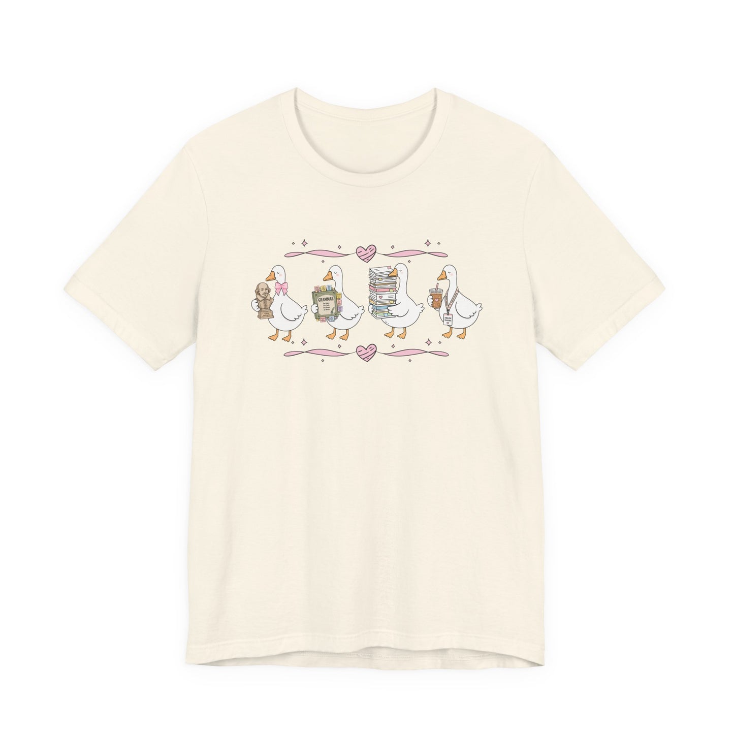 Bella + Canvas 3001 t-shirt in Natural featuring a coquette English teacher goose design. Four white geese carry a classic literature bust, a grammar book, a stack of books and papers, and an iced coffee with an English teacher lanyard. Pink hearts and ribbon accents add a charming touch, making this shirt a thoughtful gift for English teachers, teacher appreciation events, and back-to-school season.