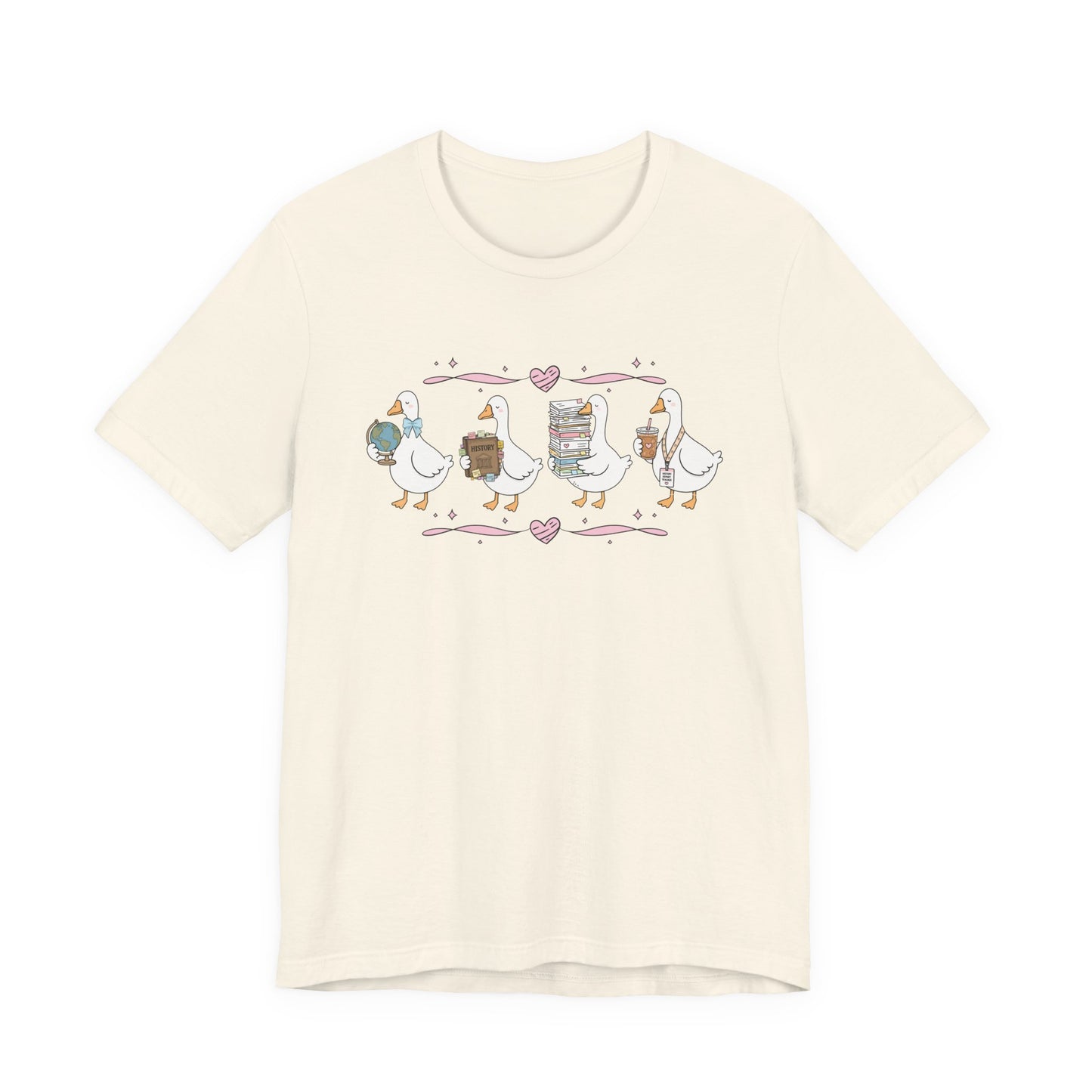 Bella + Canvas 3001 t-shirt in Natural featuring a coquette history teacher goose design. Four white geese carry a globe, history textbook, stack of classroom papers, and iced coffee with a history teacher lanyard. Pink hearts and ribbon accents add a charming vintage-inspired touch, making this shirt a thoughtful gift for history teachers, back-to-school season, and teacher appreciation occasions.