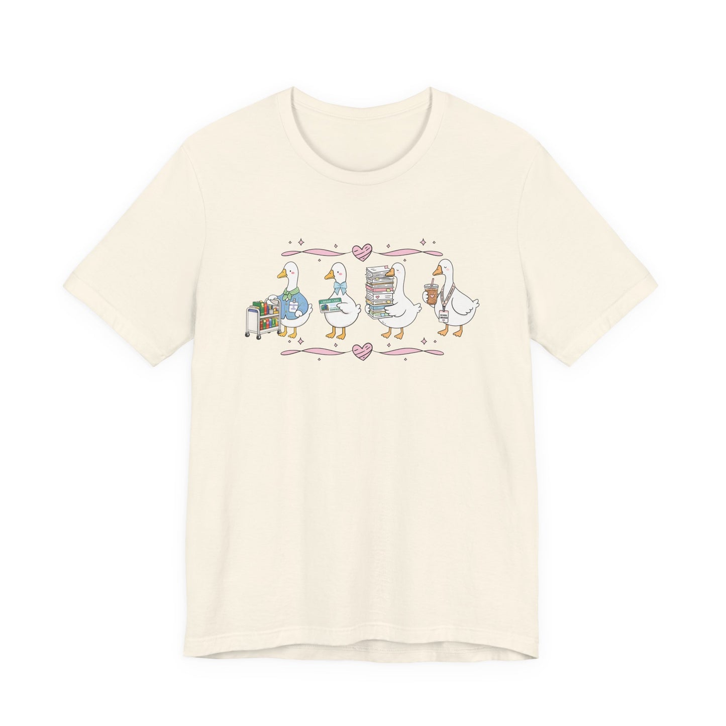Bella + Canvas 3001 t-shirt in Natural featuring a coquette librarian goose design. Four white geese display a library book cart, library card, stack of books, and iced coffee with a school librarian badge. Pink hearts and ribbon accents create a sweet bookish aesthetic, making this librarian shirt perfect for school librarians, media specialists, library staff, book lovers, teacher appreciation gifts, and back-to-school outfits.