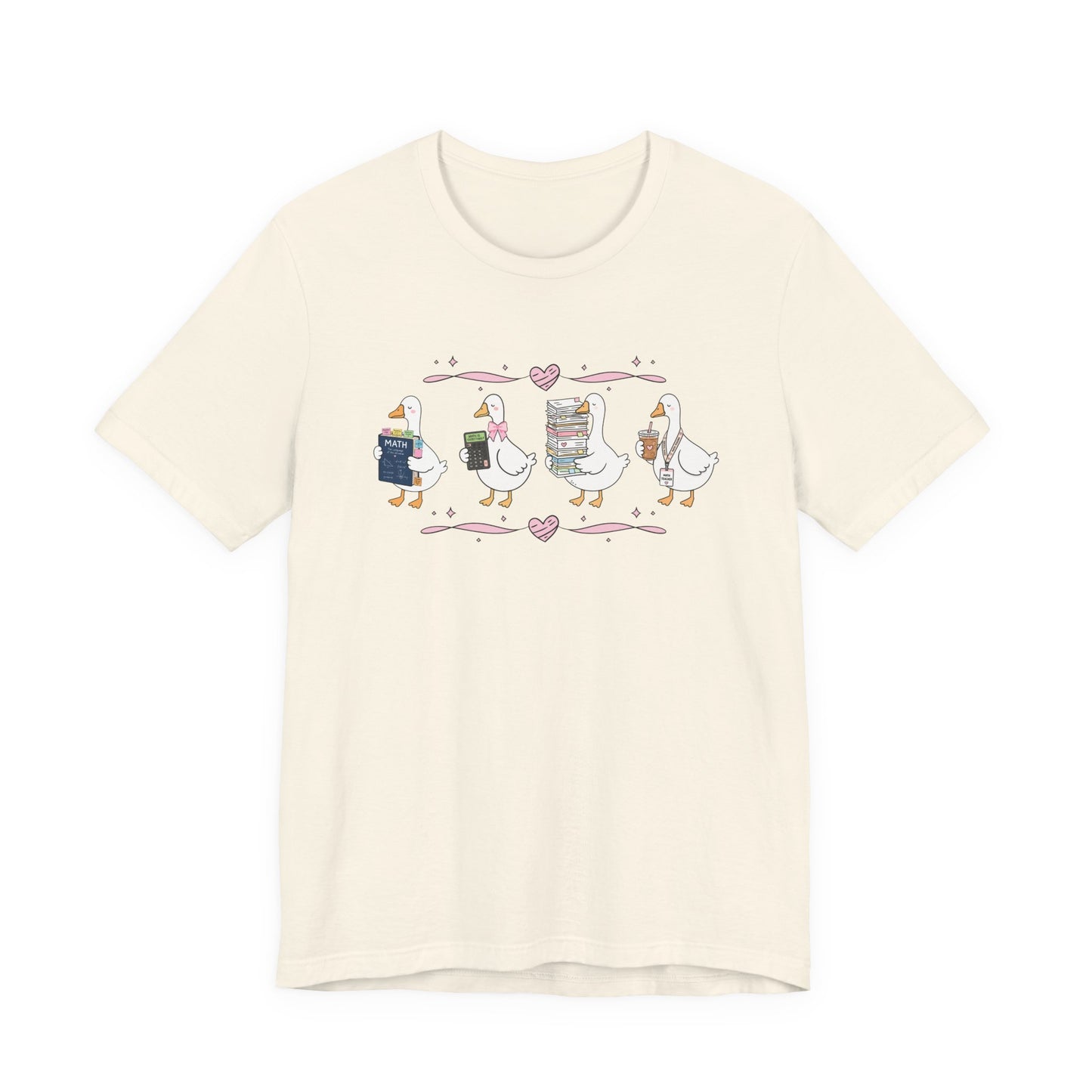 Bella + Canvas 3001 t-shirt in Natural featuring a coquette math teacher goose design. Four white geese carry a math textbook, calculator, stack of papers, and iced coffee with a teacher lanyard. Pink bows and heart accents add a playful classroom-inspired touch. This cute math teacher shirt makes a great back-to-school outfit, teacher appreciation gift, and everyday educator tee.