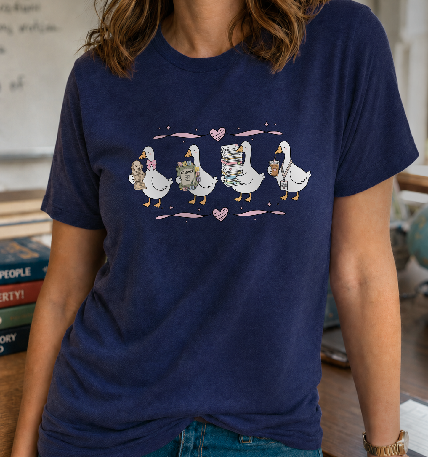 Bella + Canvas 3001 unisex t-shirt in Navy featuring four adorable geese with English teacher-themed accessories, including a Shakespeare bust, grammar book, stack of books, and iced coffee. Accented with pink hearts and ribbons, this cute English teacher shirt is perfect for literature teachers, book lovers, and classroom wear.