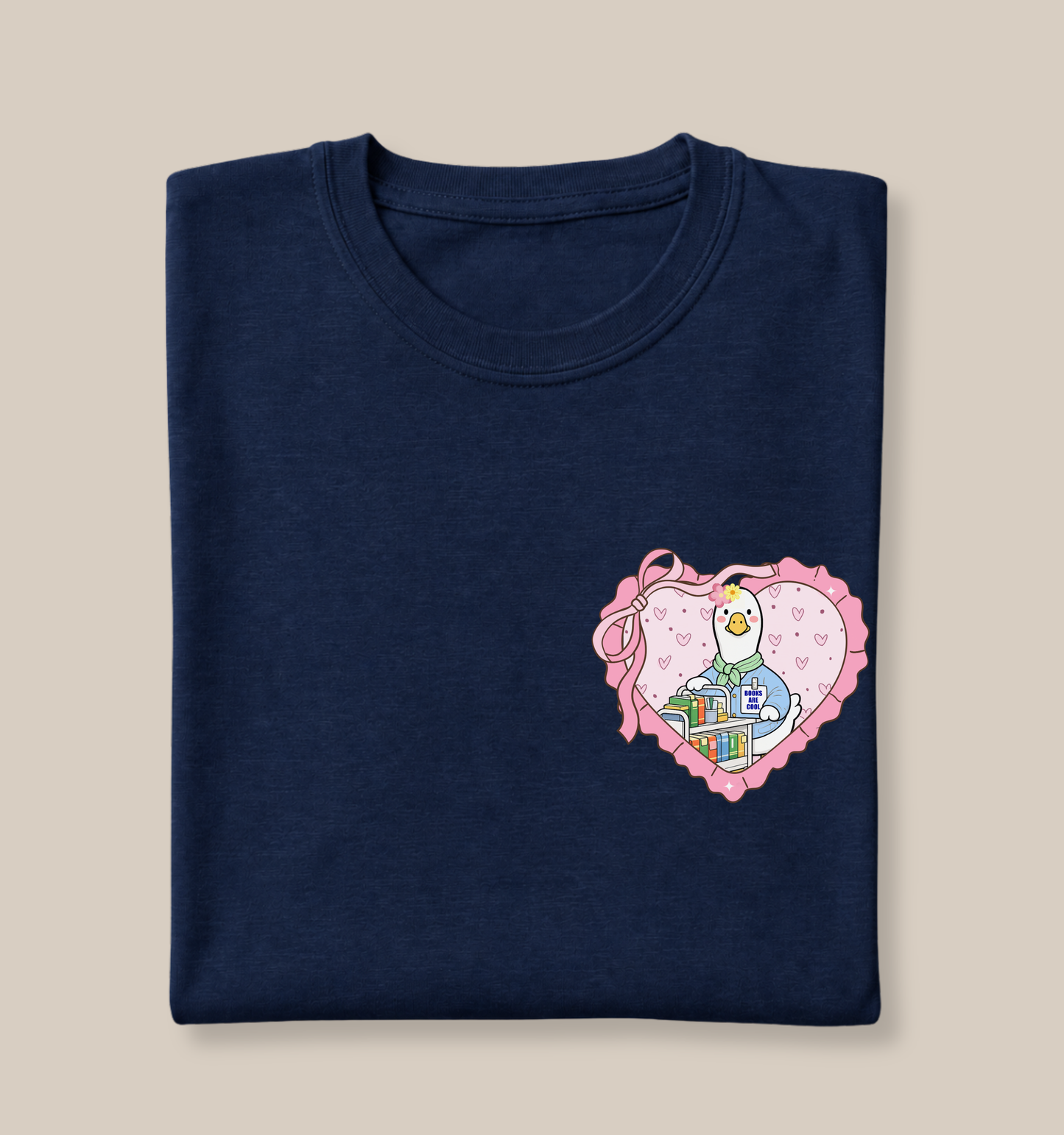 Bella + Canvas 3001 t-shirt in Navy featuring a coquette school librarian goose heart pocket design. The artwork shows a white goose standing behind a rolling book cart and holding a book inside a pink heart with ribbon accents and pastel details. Perfect for school librarians, media specialists, library assistants, book lovers, and back-to-school educator gifts.