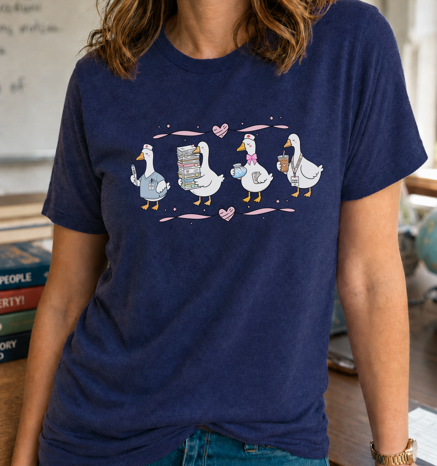Bella + Canvas 3001 unisex t-shirt in Navy featuring a whimsical parade of four geese dressed as school nurses. The geese carry a thermometer, stacks of paperwork, a pill bottle and medicine cup, and an iced coffee with a school nurse badge. Pink hearts and ribbon accents complete this cute school nurse graphic tee, perfect for Nurse Appreciation Week, back-to-school, or everyday wear.