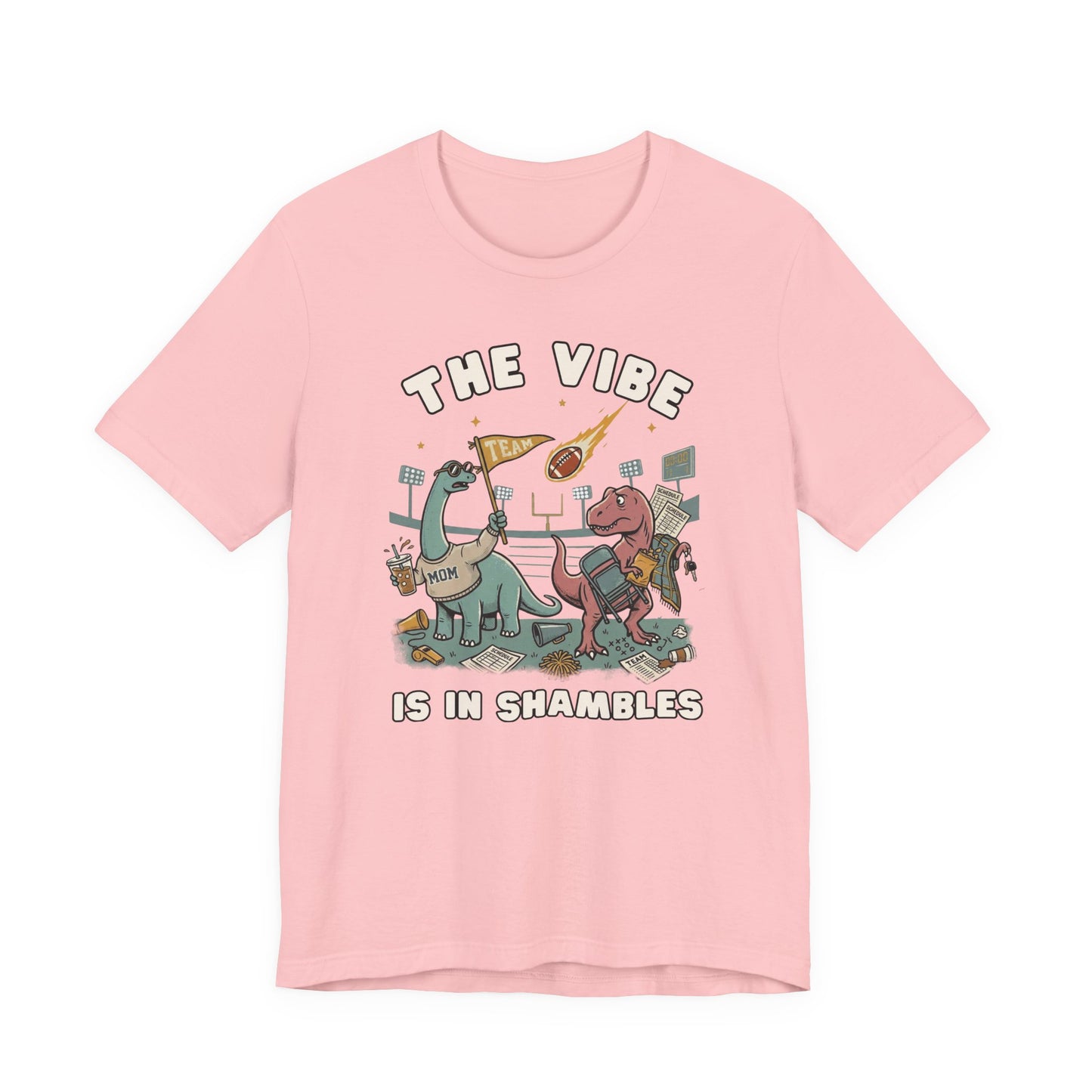 Bella + Canvas 3001 pink t-shirt featuring two overwhelmed teacher dinosaurs in a chaotic classroom surrounded by books, papers, pencils, and school supplies. Funny teacher graphic tee with "The Vibe Is In Shambles" design, perfect for elementary teachers, middle school teachers, high school teachers, educators, and back-to-school season.