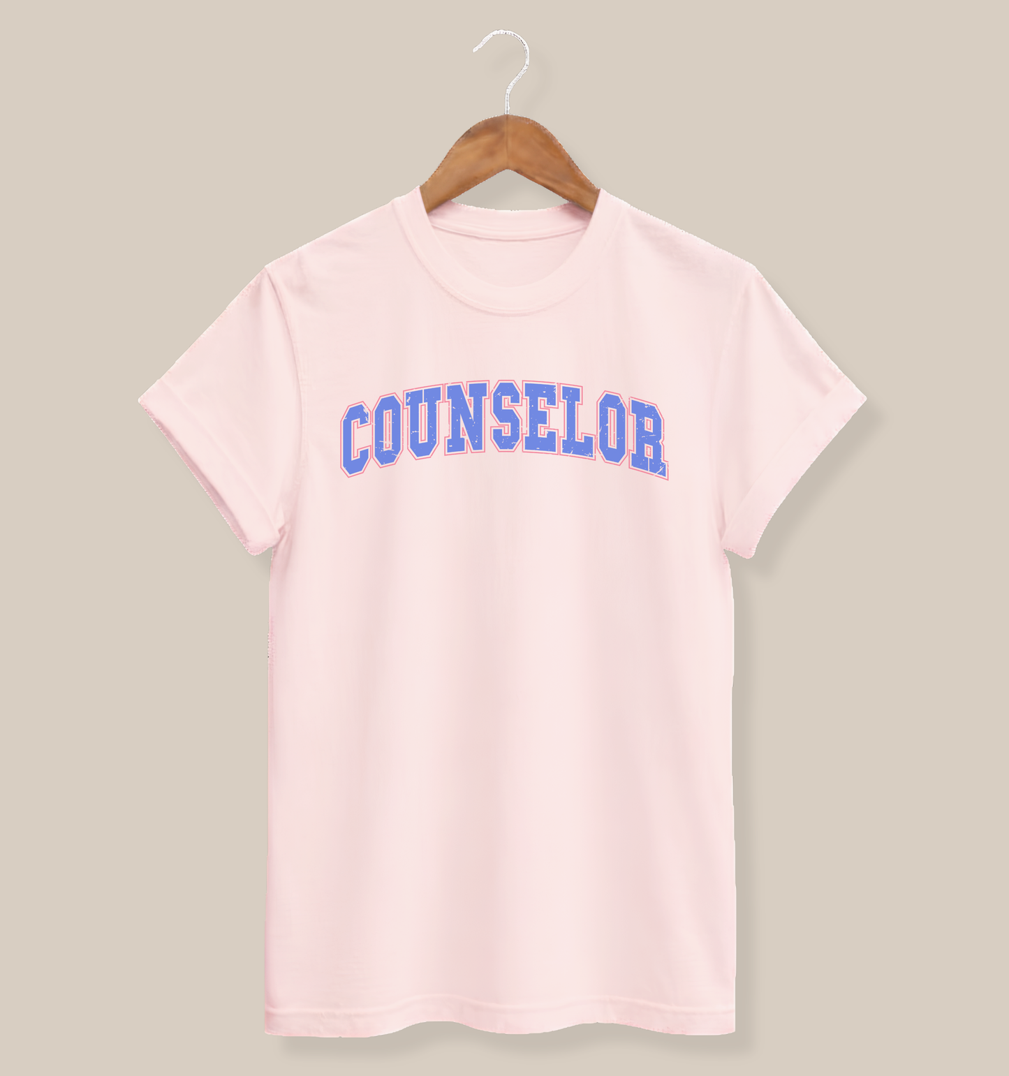 Bella + Canvas 3001 unisex t-shirt in Soft Pink featuring a distressed varsity-style "Counselor" graphic in blue and pink across the chest. A retro-inspired graphic tee for school counselors, guidance counselors, and education professionals, perfect for school days, casual wear, and appreciation gifts.