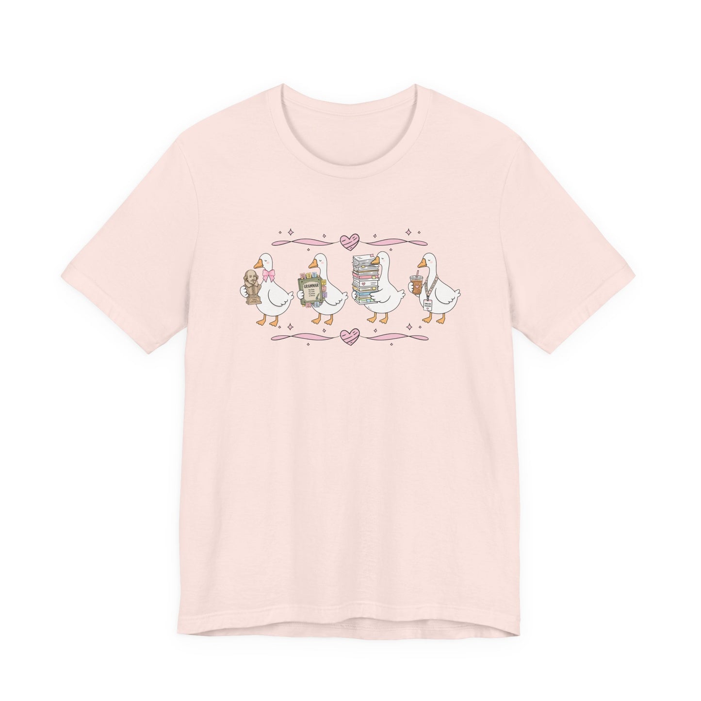 Bella + Canvas 3001 t-shirt in Soft Pink featuring a coquette English teacher goose design. Four white geese carry a classic literature bust, a grammar book, a stack of books and papers, and an iced coffee with an English teacher lanyard. Pink hearts and ribbon accents add a whimsical touch, making this cute English teacher shirt perfect for back-to-school outfits, teacher appreciation gifts, and everyday classroom wear.