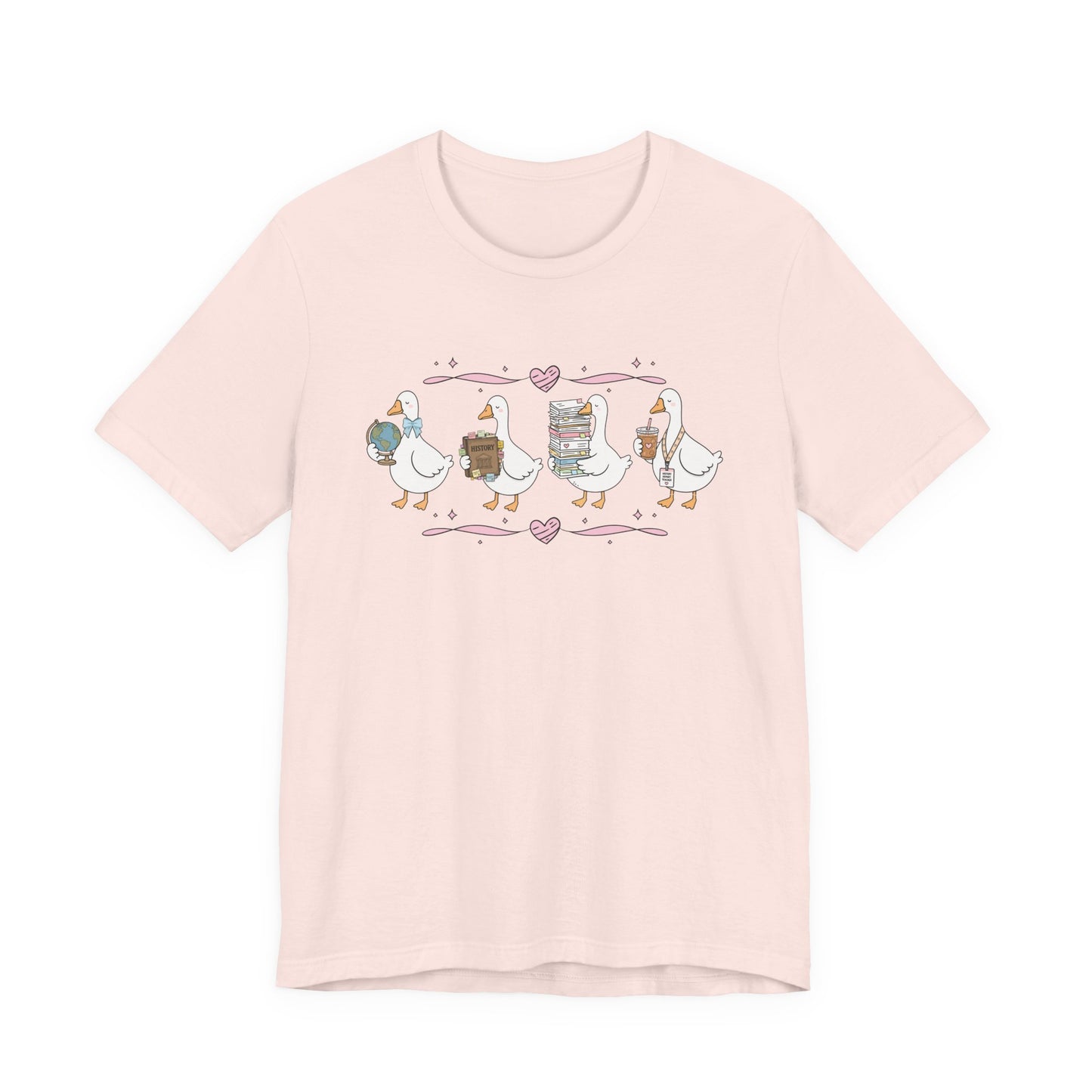 Bella + Canvas 3001 t-shirt in Soft Pink featuring a coquette history teacher goose design. Four white geese carry a globe, history textbook, stack of classroom papers, and iced coffee with a history teacher lanyard. Pink hearts and ribbon accents create a sweet, feminine look, making this shirt perfect for history teachers, teacher appreciation gifts, and back-to-school outfits.