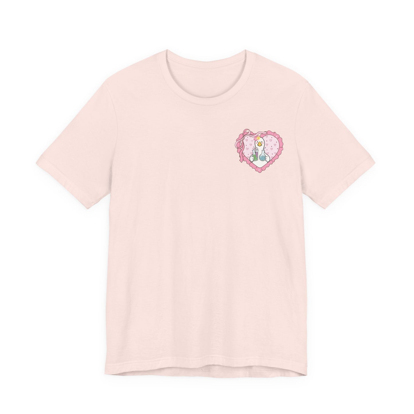 Bella + Canvas 3001 t-shirt in Soft Pink featuring a coquette science teacher goose heart design on the left chest. White goose with laboratory beakers inside a pink heart with bow accents. Great for science teachers, STEM educators, and classroom wear.