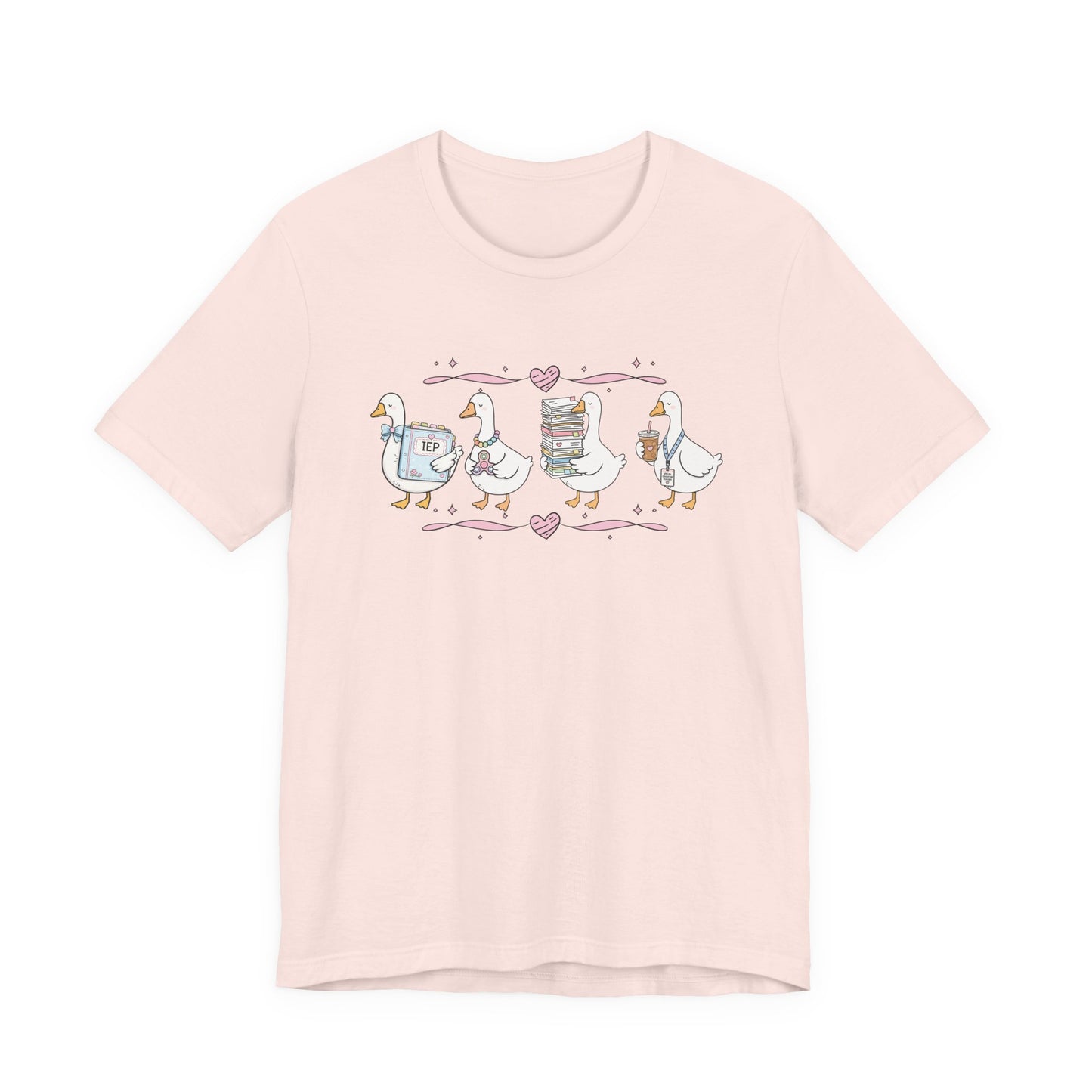 Bella + Canvas 3001 t-shirt in Soft Pink featuring a coquette special education teacher goose design. Four white geese hold an IEP binder, sensory fidget toy, stack of paperwork, and iced coffee with a special education teacher lanyard. Pink hearts and ribbon accents add a sweet touch. This cute SPED teacher shirt is perfect for special education teachers, back-to-school outfits, teacher appreciation gifts, and everyday classroom wear.