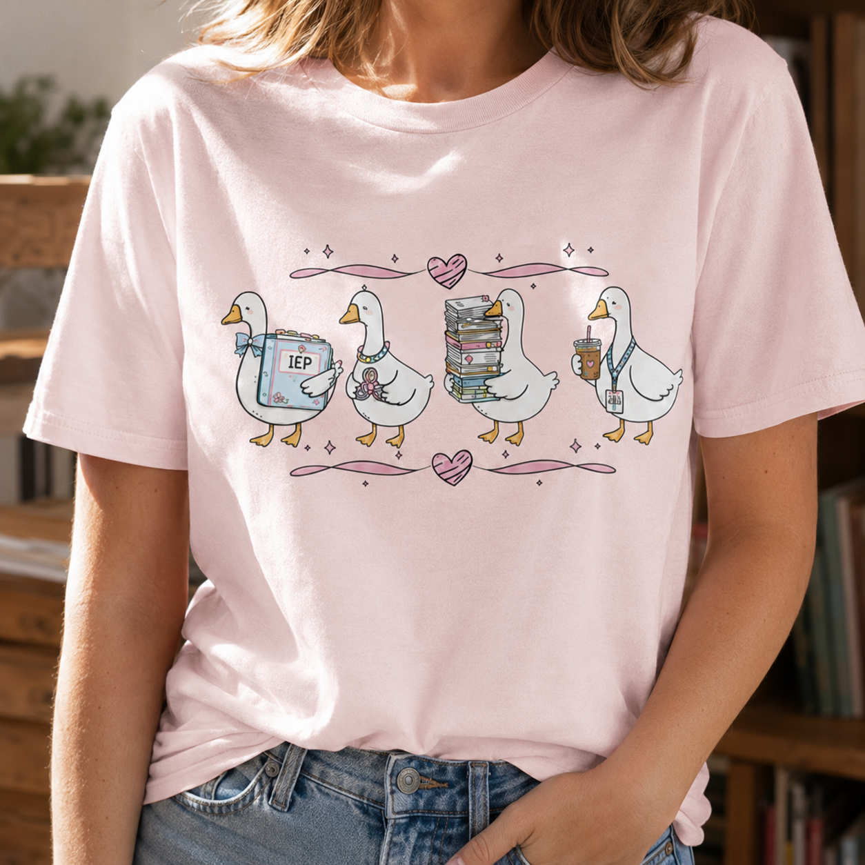 Bella + Canvas 3001 unisex t-shirt in Soft Pink featuring four adorable teacher geese carrying an IEP binder, stethoscope, stack of books, and coffee. A cute special education teacher shirt perfect for SPED teachers, school staff, back-to-school, and everyday classroom wear.