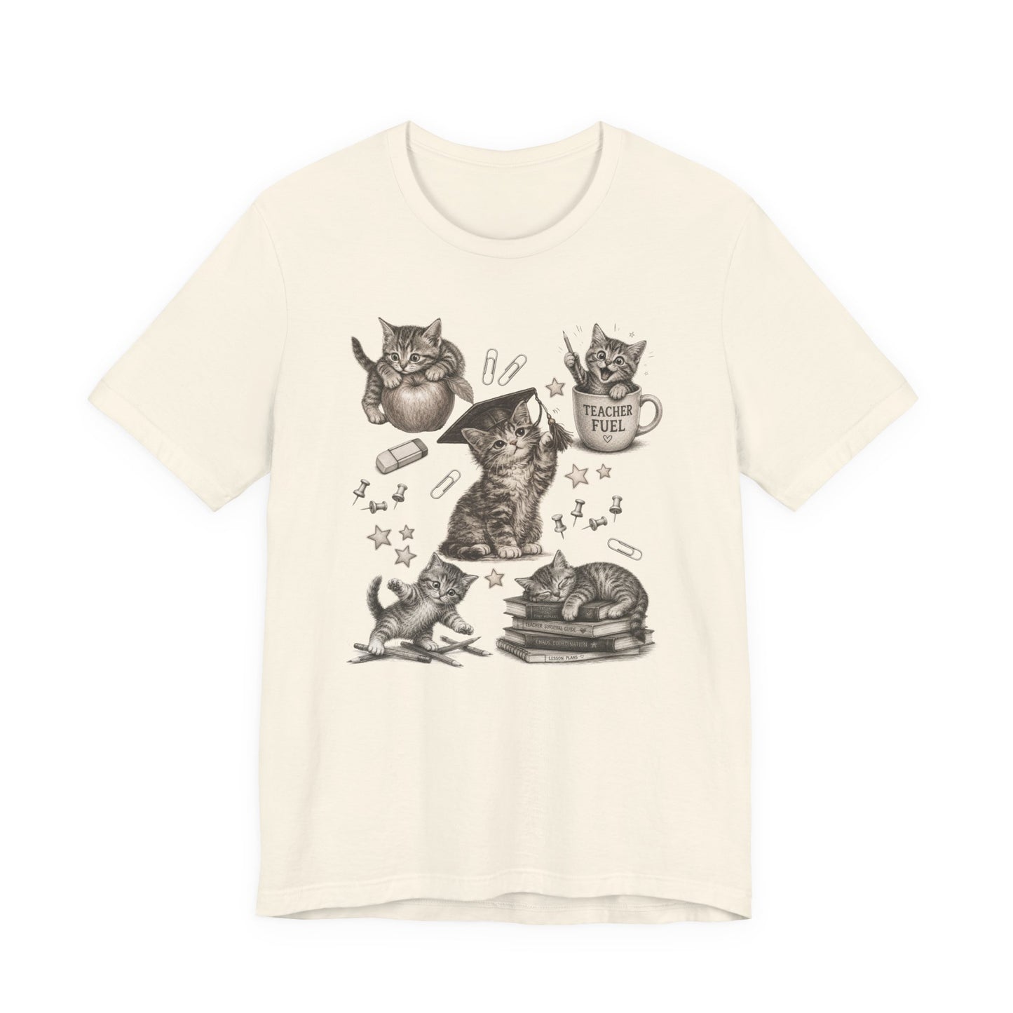 Bella + Canvas 3001 t-shirt in natural featuring detailed vintage-style kitten illustrations with school-themed elements including books, pencils, paper clips, push pins, stars, and a “Teacher Fuel” coffee mug.