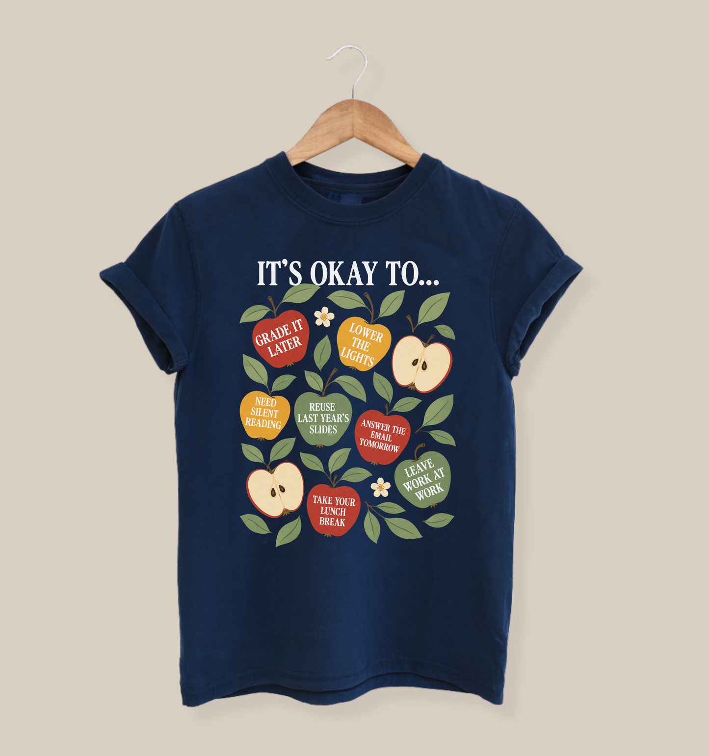 Bella + Canvas 3001 t-shirt in navy featuring colorful apple illustrations with teacher self care sayings including “Grade It Later,” “Take Your Lunch Break,” and “Leave Work at Work.”
