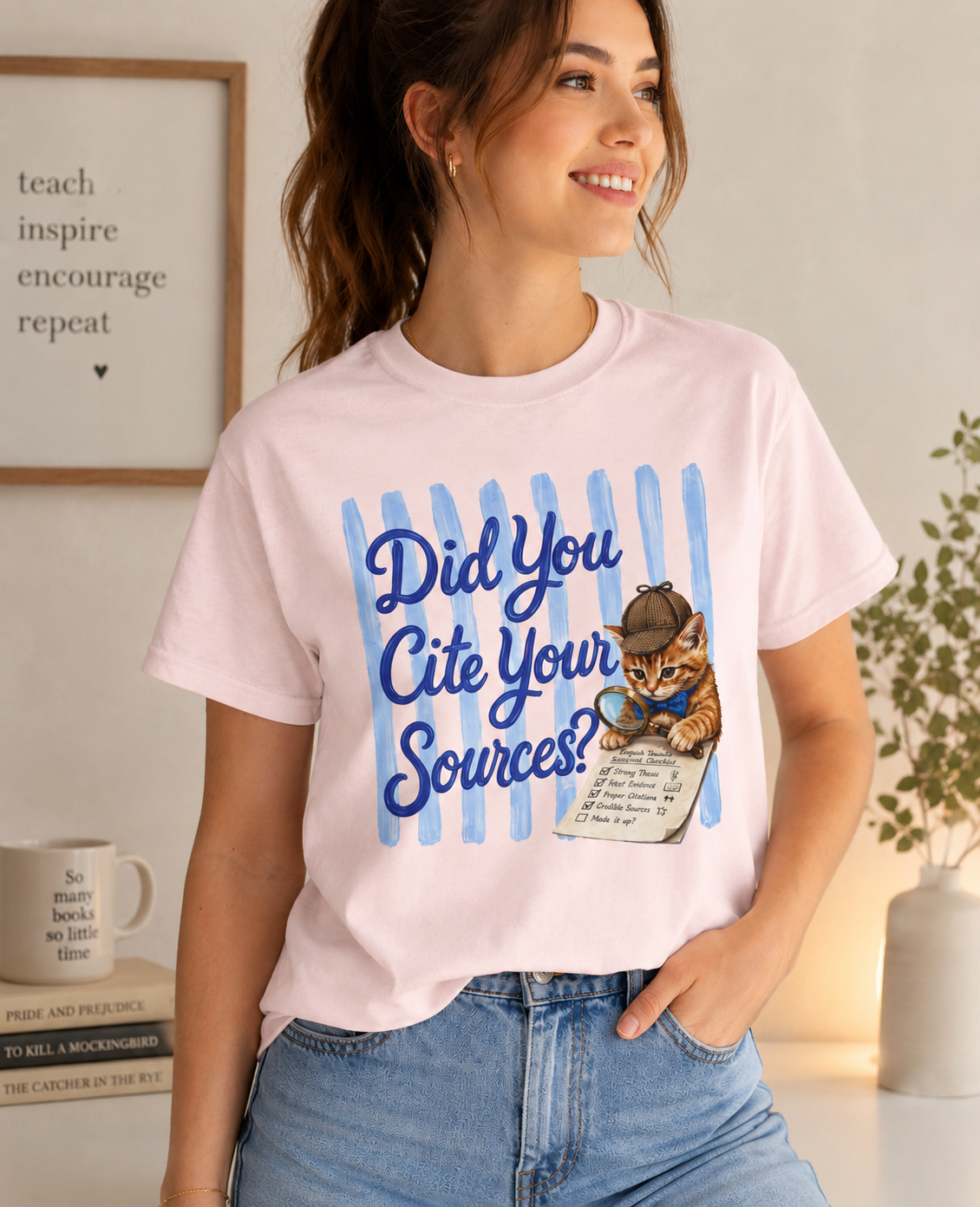 Bella + Canvas 3001 t-shirt in soft pink featuring the phrase “Did You Cite Your Sources?” in blue script with a detective kitten holding a magnifying glass and reviewing a checklist. Funny English teacher shirt for educators, librarians, reading specialists, language arts teachers, and book lovers.