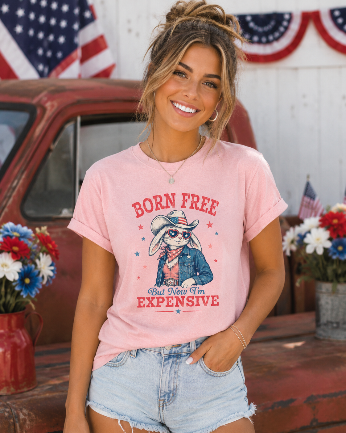 Adult Comfort Colors blossom pink t-shirt featuring a vintage patriotic bunny cowgirl graphic with heart sunglasses, denim jacket, and cowboy hat paired with the phrase “Born Free But Now I’m Expensive” in retro red and blue lettering.