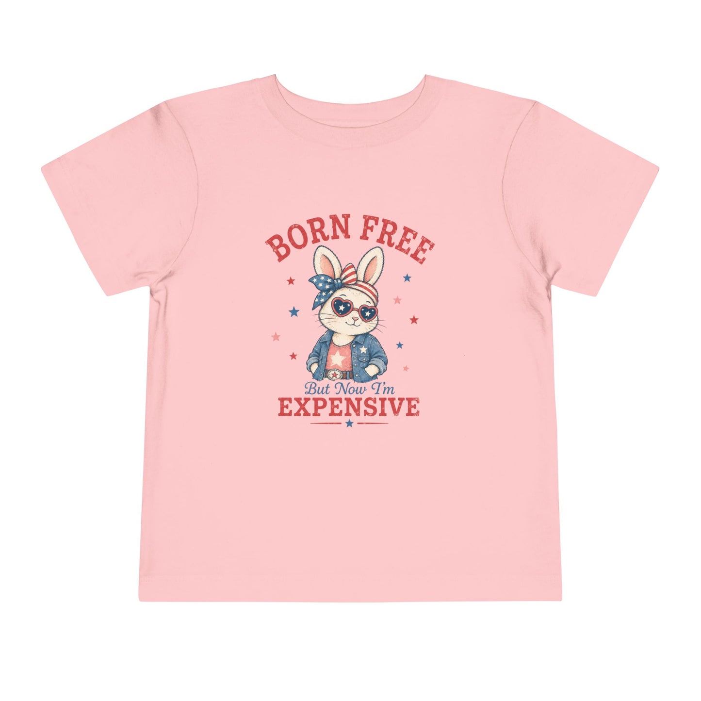 Bella + Canvas toddler soft pink t-shirt featuring a patriotic bunny graphic with heart sunglasses, stars and stripes bow, denim jacket, and the phrase “Born Free But Now I’m Expensive” in vintage red and blue lettering.