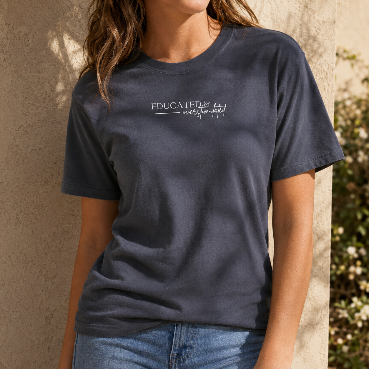 CC 1717 garment-dyed t-shirt in True Navy featuring the phrase "Educated & Overstimulated" in a minimalist white graphic. A soft, relaxed-fit graphic tee perfect for teachers, school counselors, librarians, educators, and anyone who appreciates witty academic humor and comfortable everyday style.