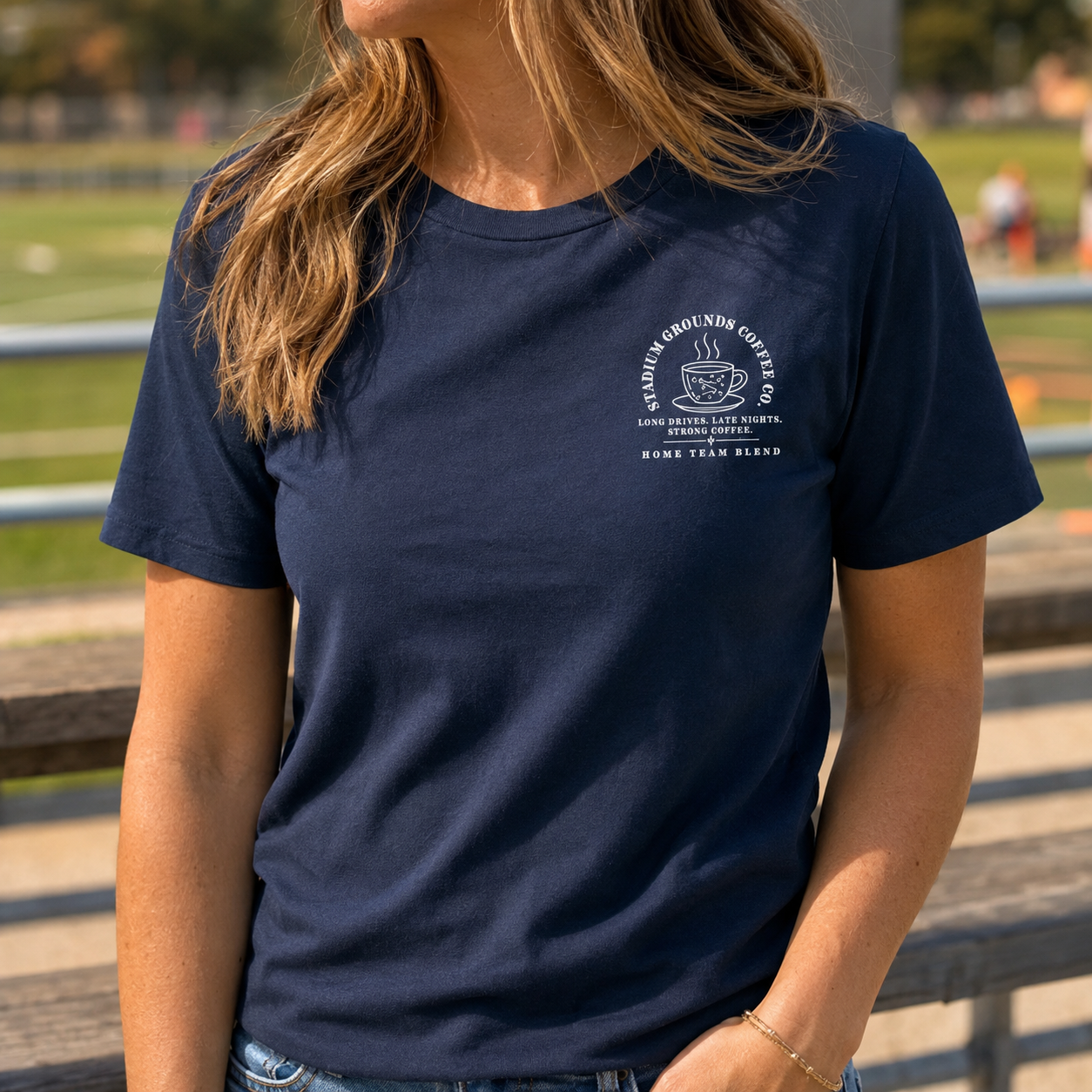 Bella + Canvas 3001 unisex t-shirt in Navy featuring a small left chest "Stadium Grounds Coffee Co." graphic with a coffee cup and the phrase "Long Drives. Late Nights. Strong Coffee. Home Team Blend." Comfortable sports mom graphic tee perfect for game days, tournaments, travel ball, and cheering from the sidelines.