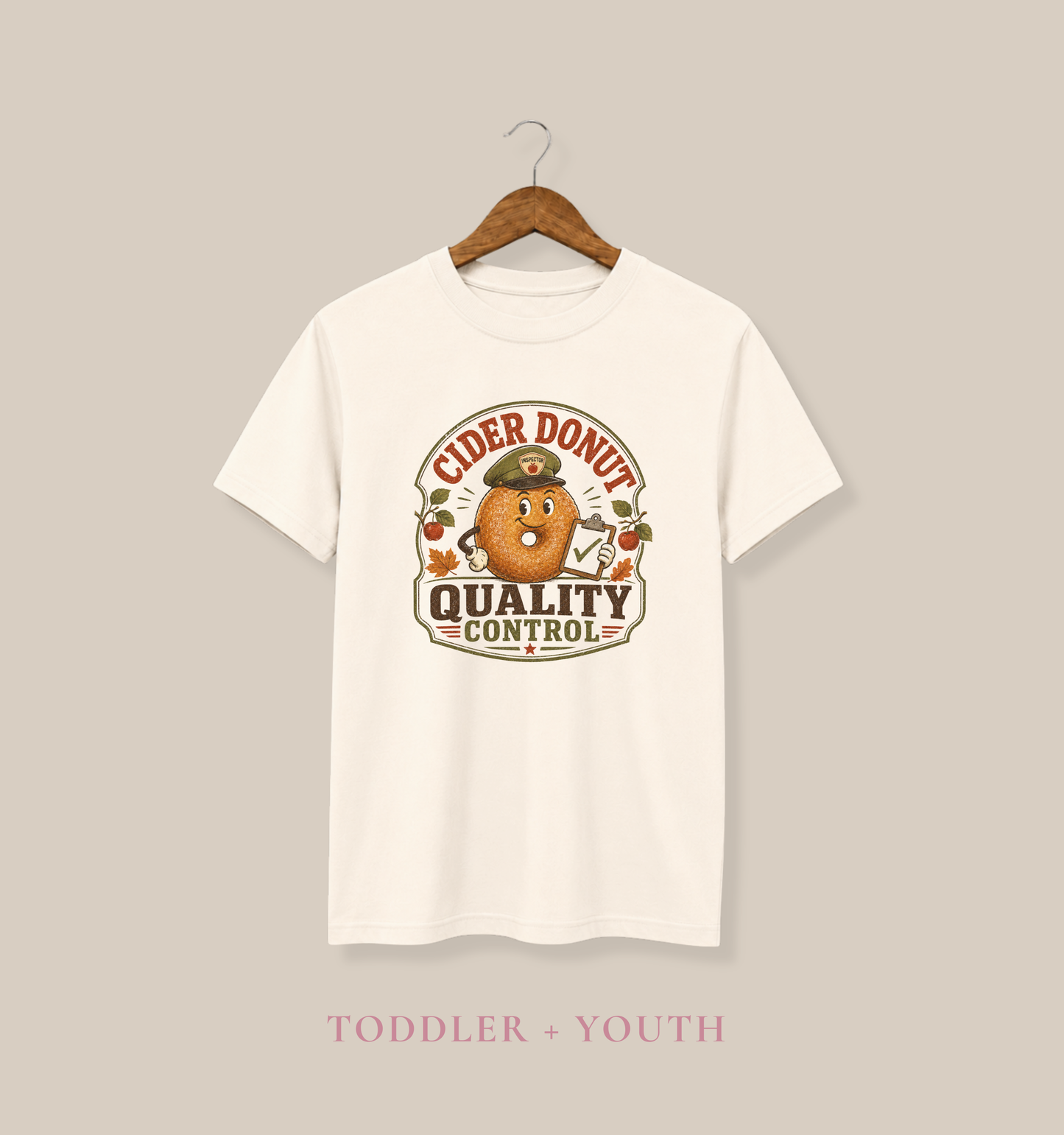 Natural toddler T-shirt featuring a vintage cider donut inspector graphic with apples, autumn leaves, and the phrase “Cider Donut Quality Control.”