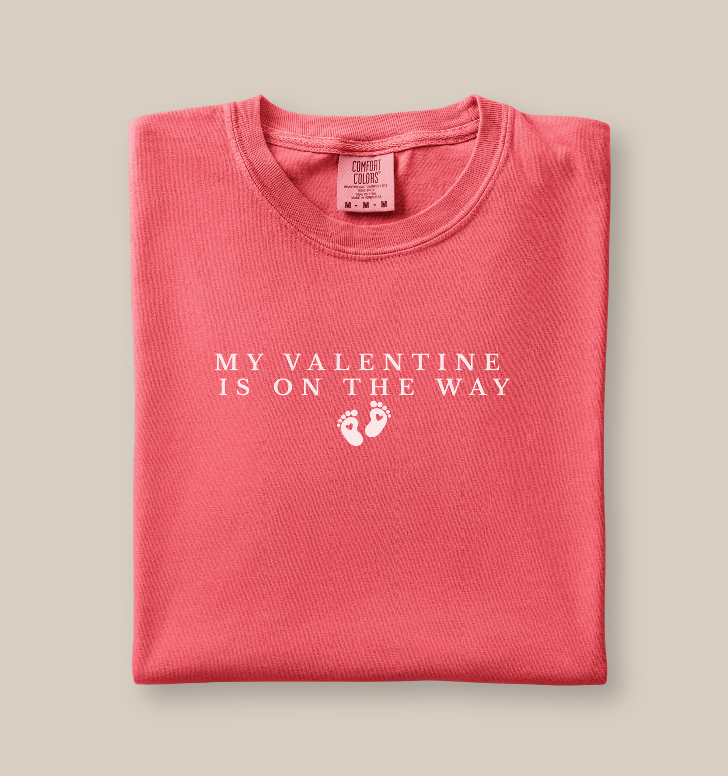 Folded shirt with 'My Valentine is on the way' text on a beige background