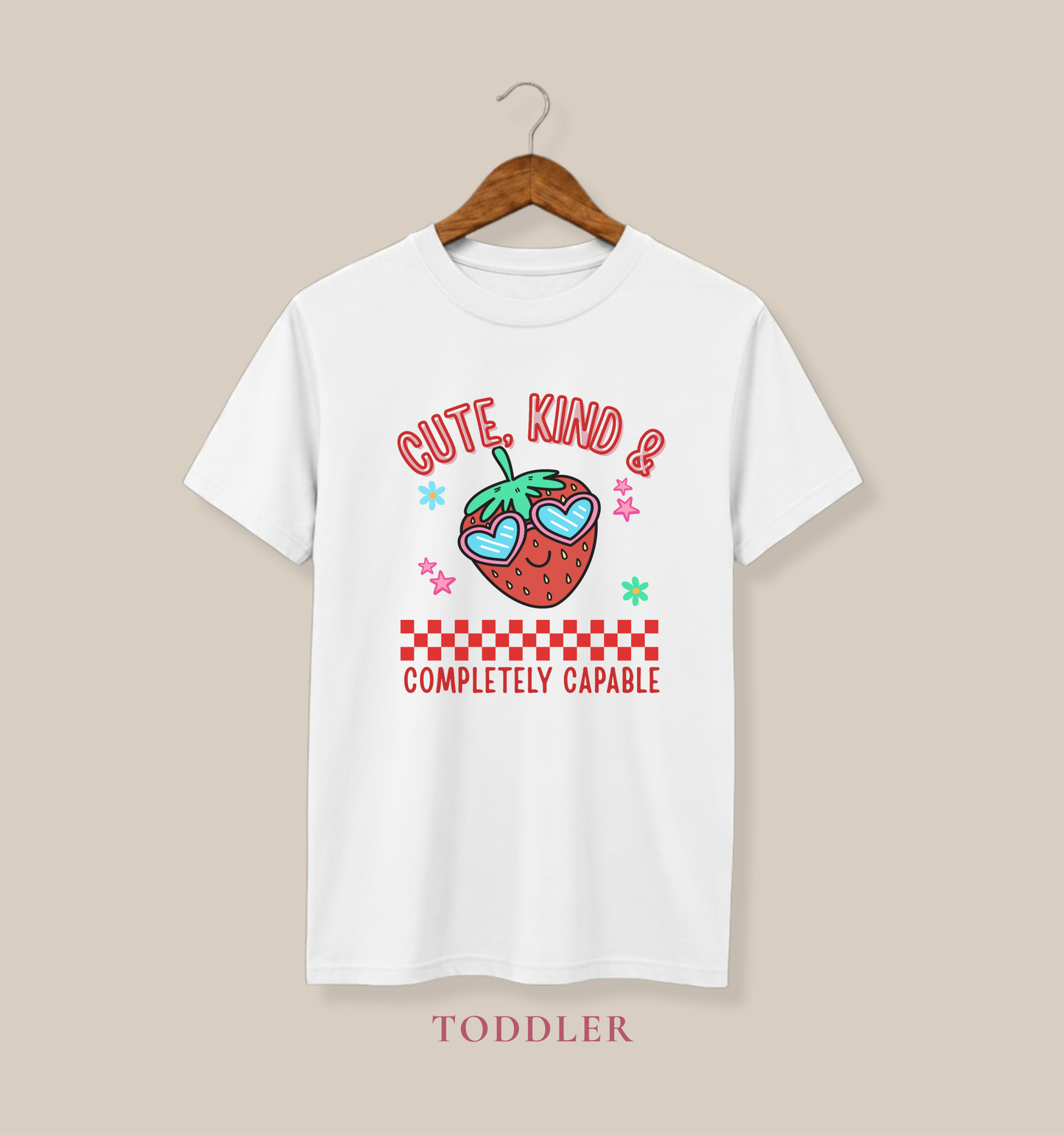 white toddler T-shirts featuring a smiling strawberry in heart-shaped sunglasses and the phrase “Cute, Kind & Completely Capable.”