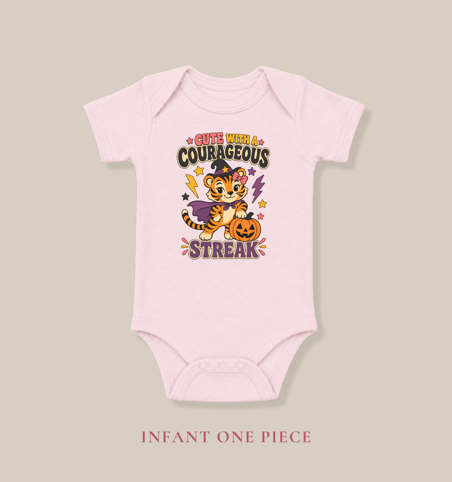 Pink baby one piece featuring a tiger dressed as a witch, a jack-o’-lantern, colorful stars, and the phrase “Cute With a Courageous Streak.”