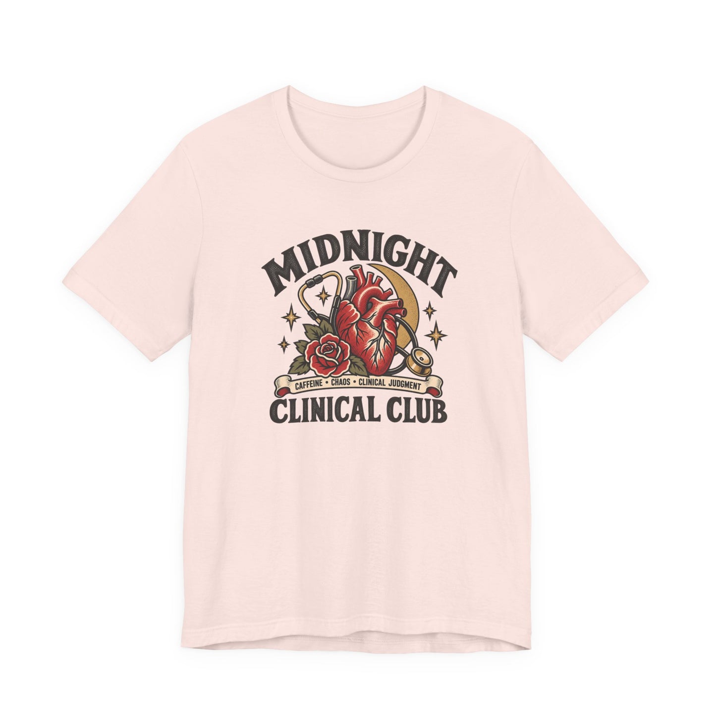 Soft pink classic fit tee displaying a Midnight Clinical Club design with a stethoscope, anatomical heart, crescent moon, stars, and rose accents.