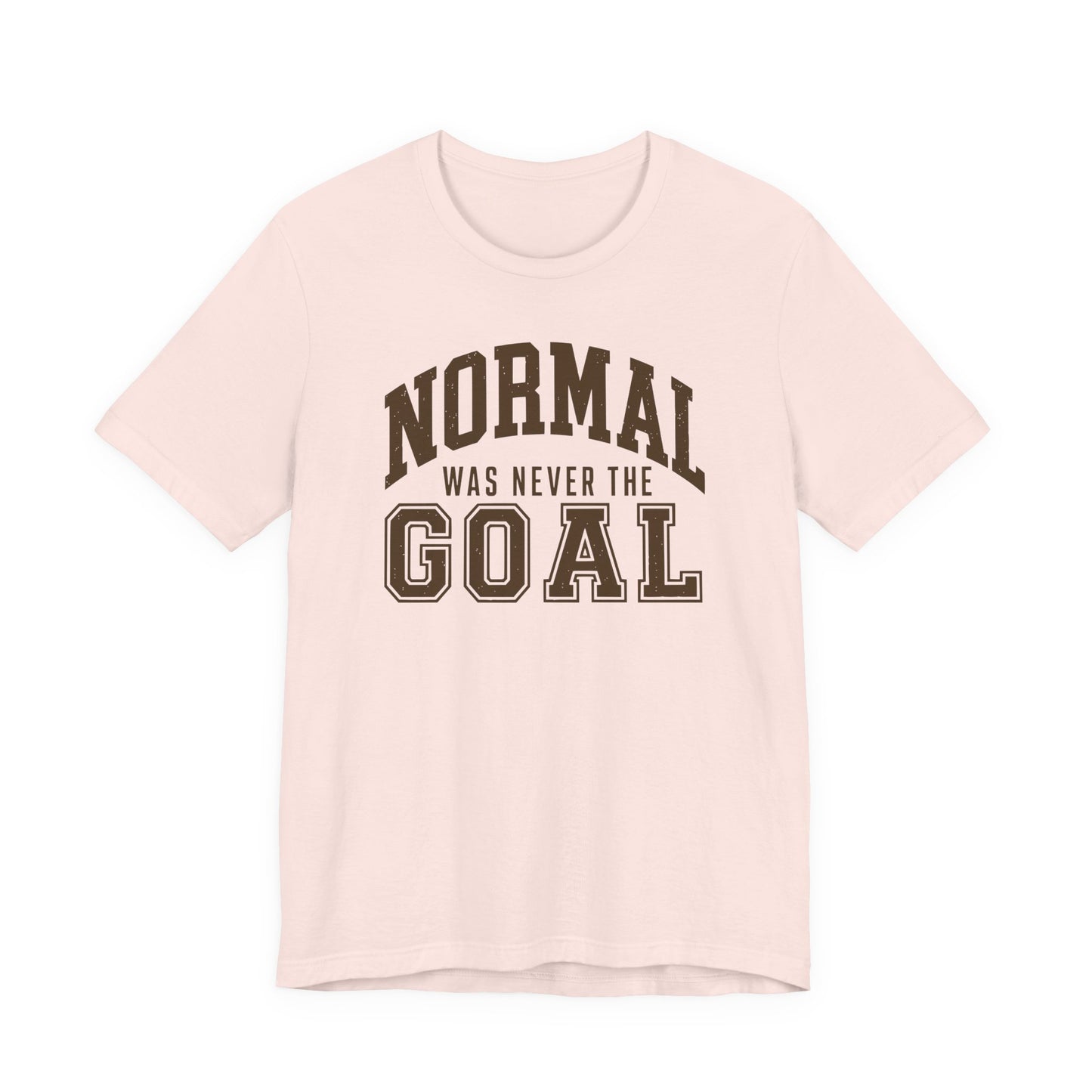 Soft pink adult T-shirt featuring bold collegiate-style typography with the playful saying “Normal Was Never the Goal.”