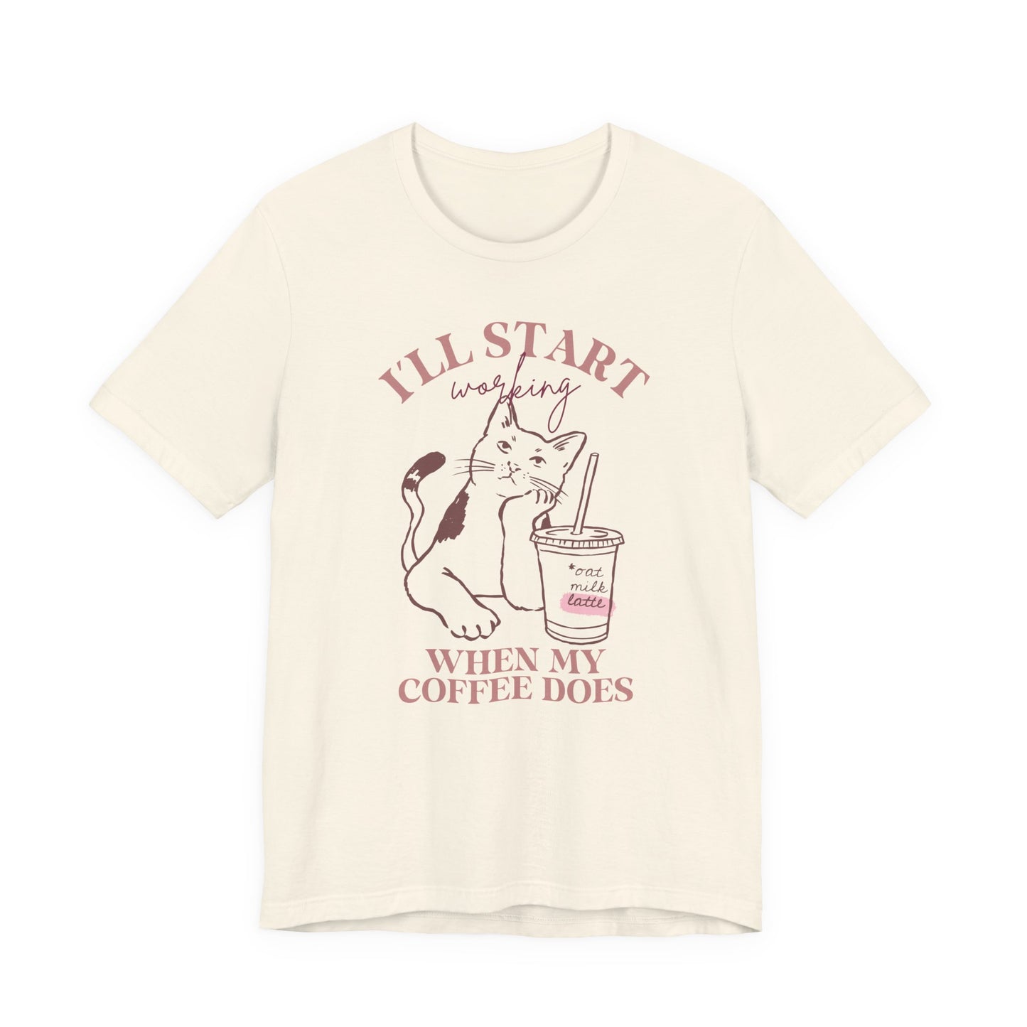 Bella + Canvas 3001 unisex t-shirt in ivory featuring an “I’ll Start Working When My Coffee Does” graphic with a cat and iced oat milk latte illustration.