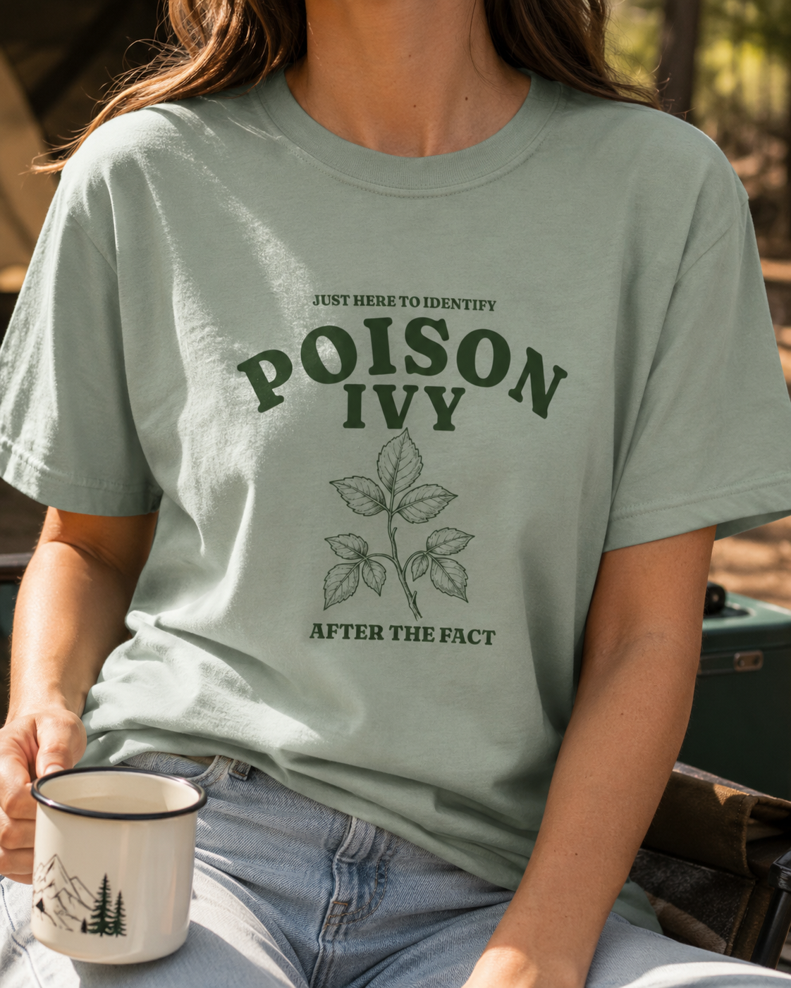 Woman wearing a bay green CC1717 adult T-shirt featuring a vintage poison ivy illustration and the humorous phrase “Just Here to Identify Poison Ivy After the Fact.”