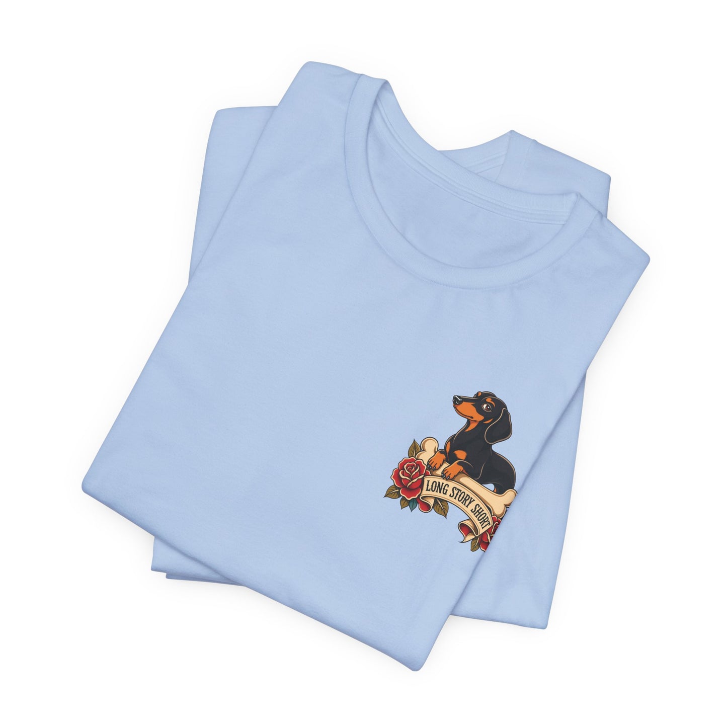 Baby blue adult T-shirt featuring a tattoo-inspired dachshund design with a bone, red roses, and a “Long Story Short” banner.