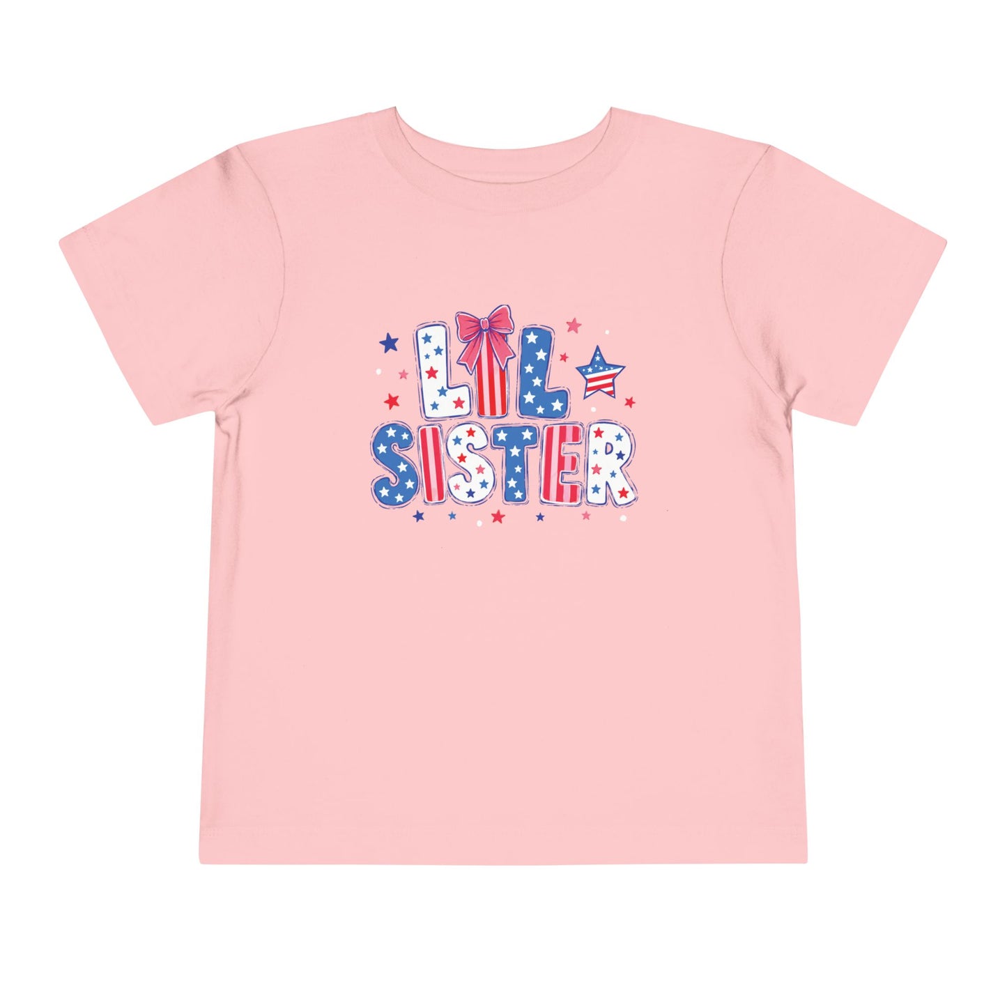 Soft pink Bella + Canvas toddler tee featuring a patriotic “Lil Sister” graphic in red, white, and blue with stars, striped lettering, and bow detail for Fourth of July sibling matching outfits.