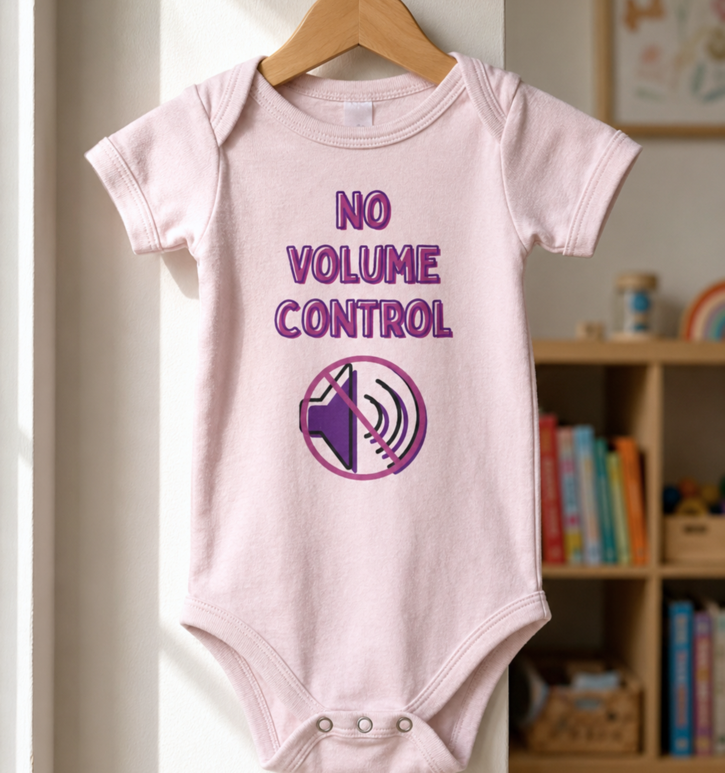Pink baby one piece featuring the phrase “No Volume Control” with a purple and pink crossed-out speaker graphic.